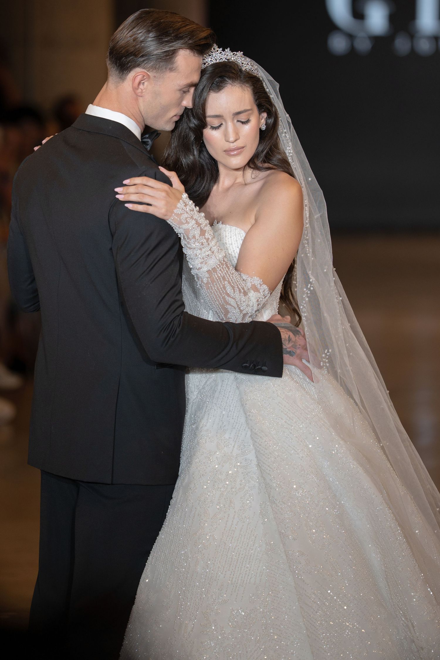 A bride and groom share an intimate dance moment at their wedding reception, with her sparkling gown catching the light.