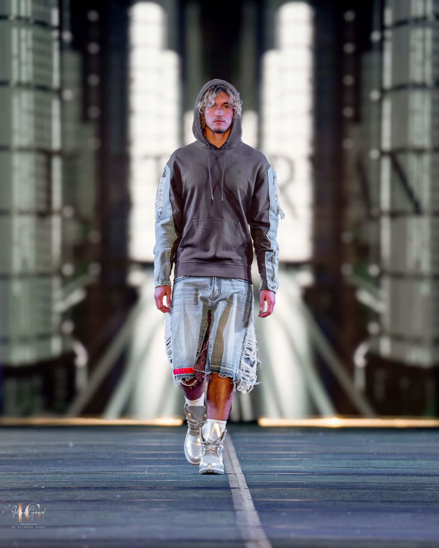Model showcases grey oversized sweater with metallic accents on dark runway.