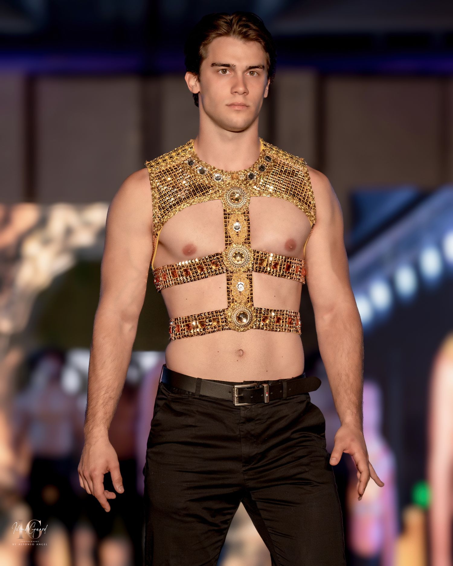 Bold gold Egyptian-inspired chest piece paired with black pants on fashion runway.
