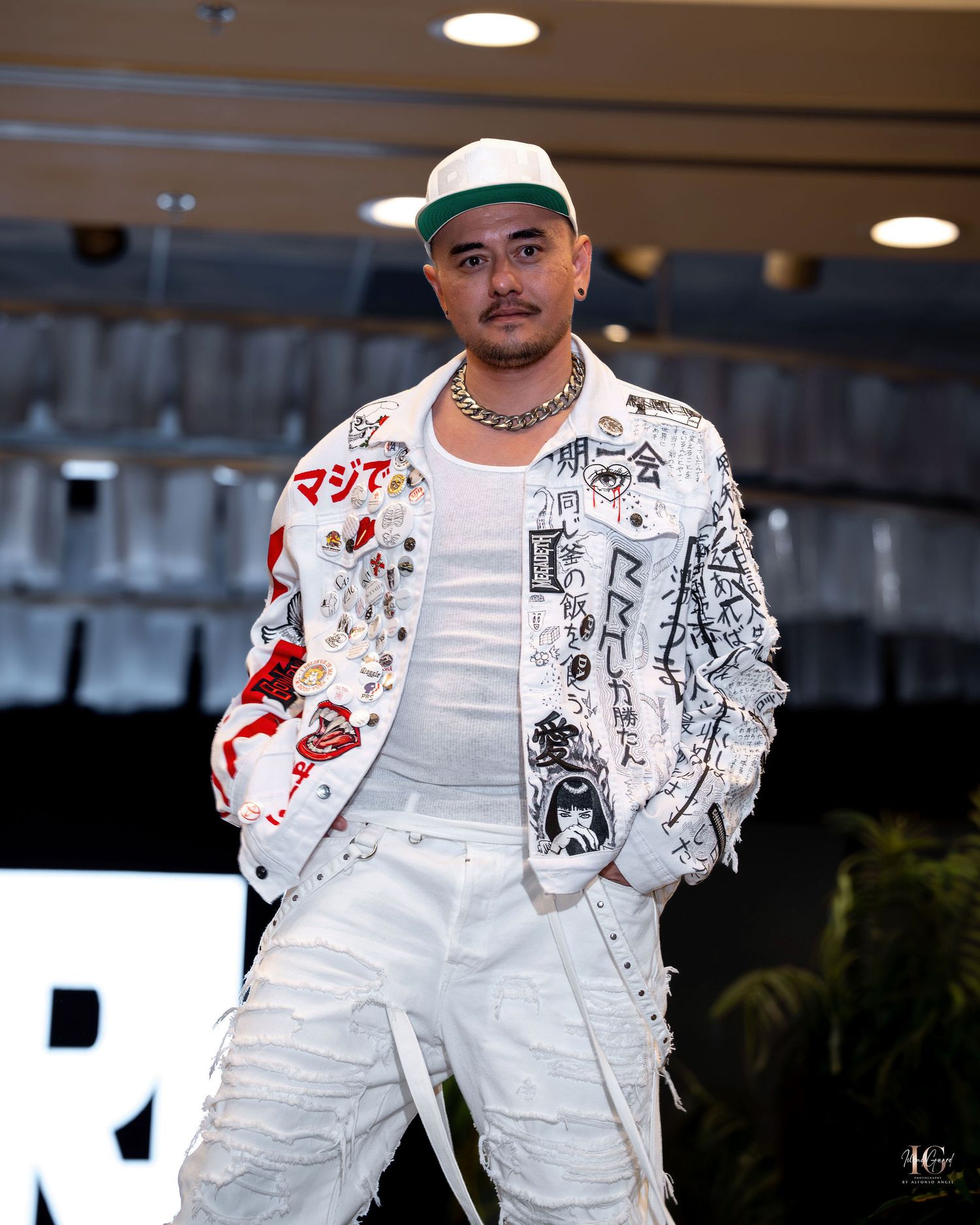Street style fashion featuring white overalls paired with a decorated white bomber jacket with graphic prints and patches.