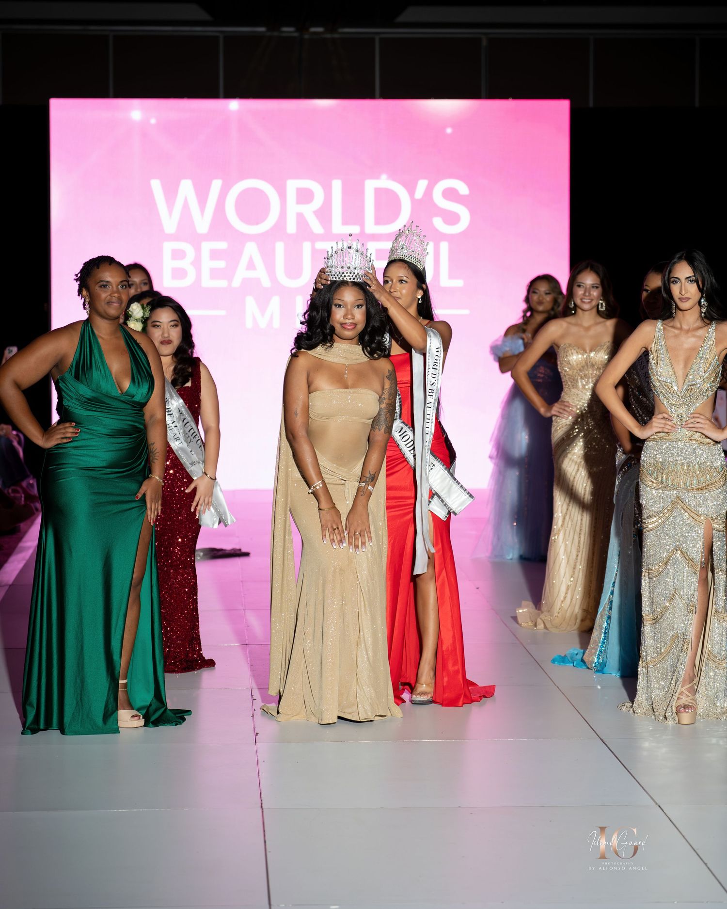 Models walk the runway wearing elegant evening gowns in emerald green and champagne colors at a fashion show.