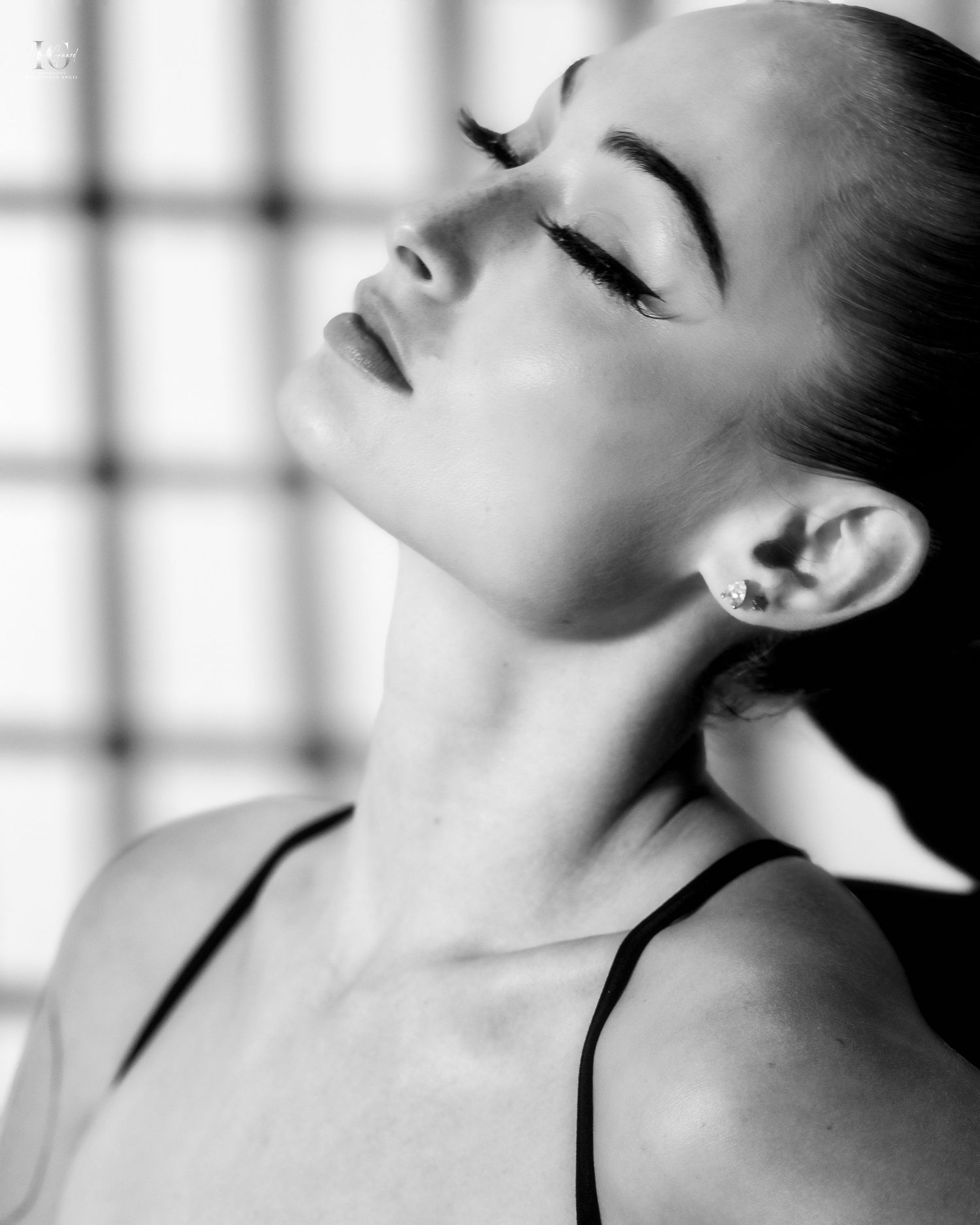 A dramatic black and white portrait showing an elegant profile pose with closed eyes against a grid pattern background.