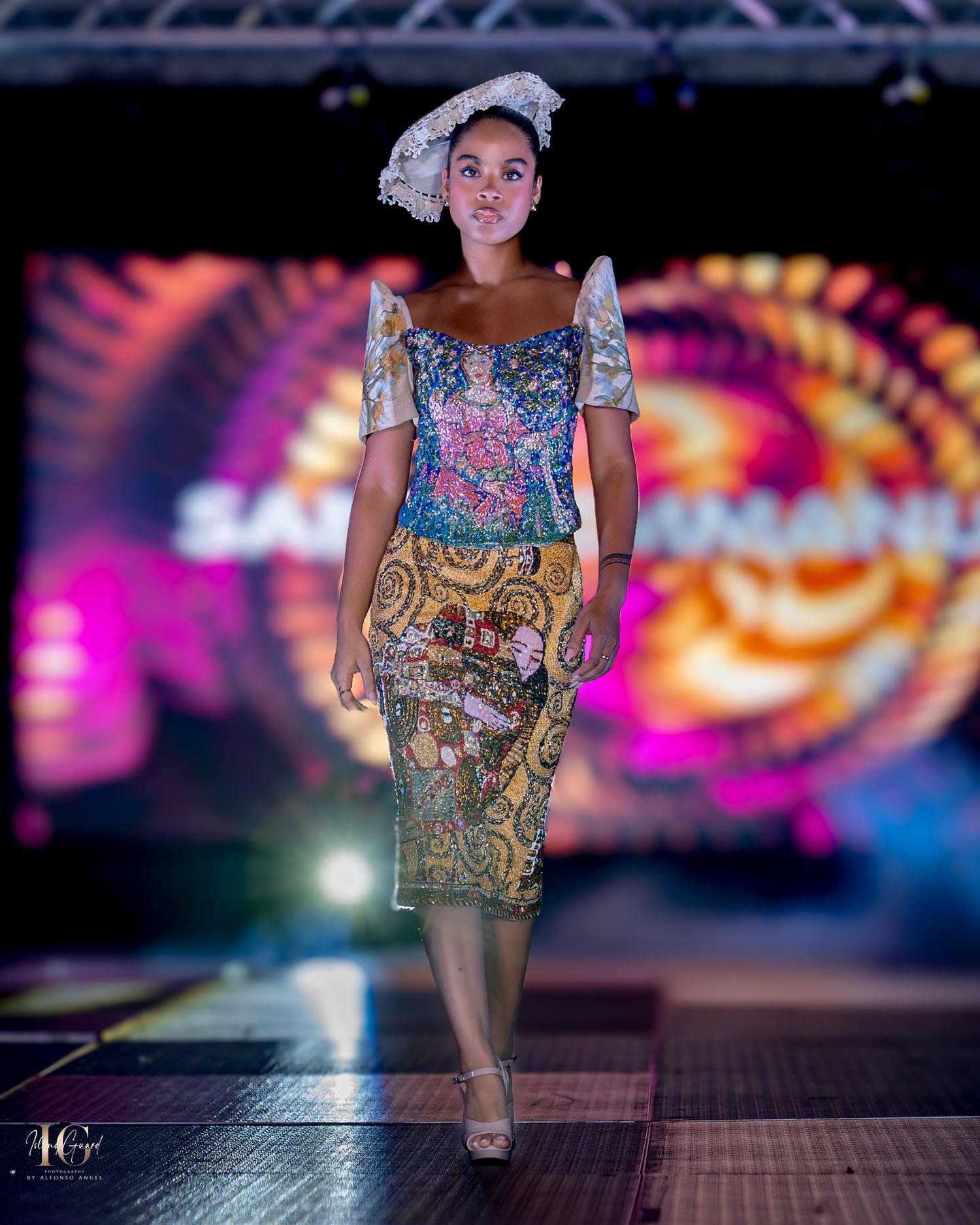 Fashion model wearing vintage-inspired floral dress with lace headpiece against colorful spiral backdrop on runway.