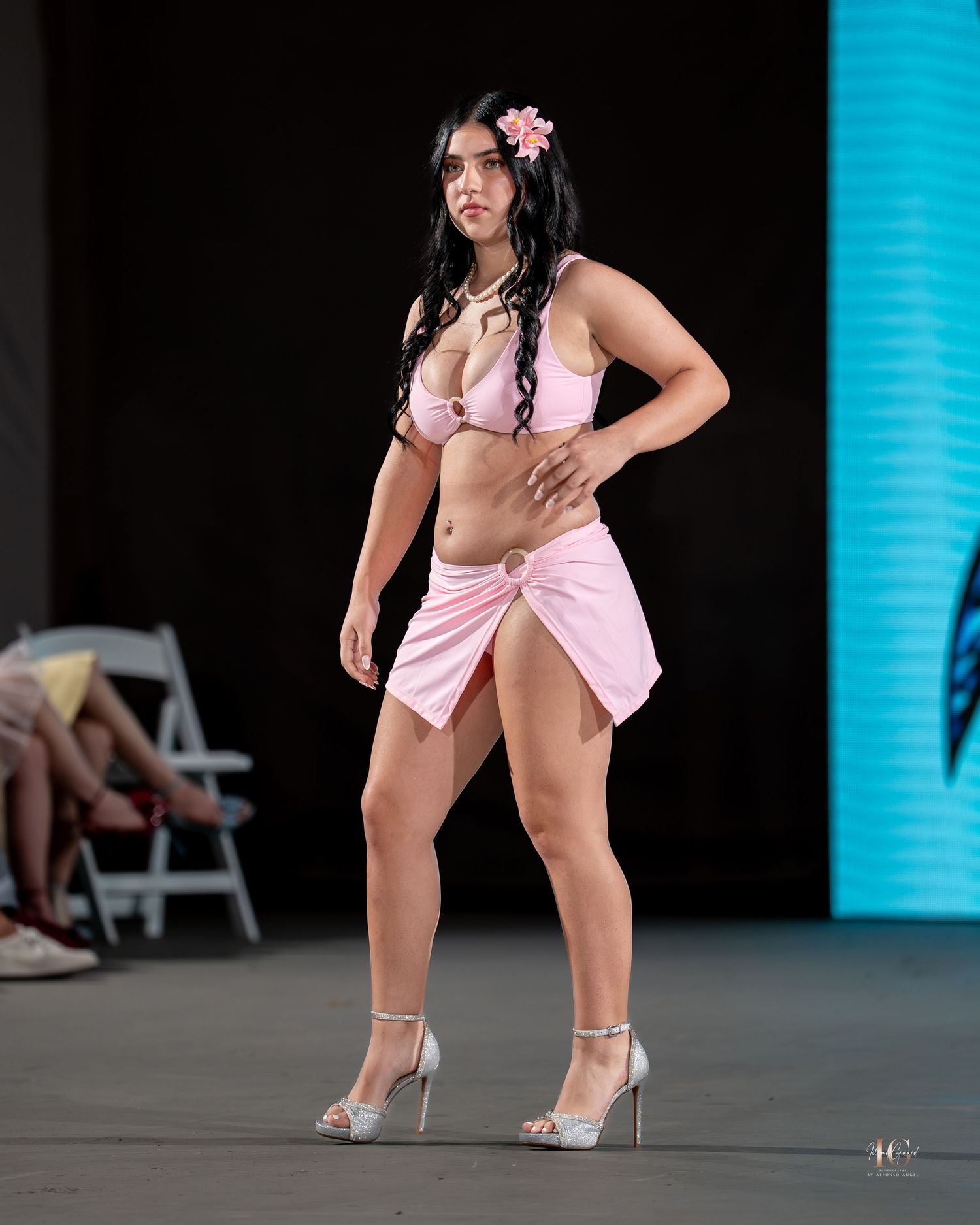 A performer in a pink outfit strikes a dynamic pose on stage during a dance routine.