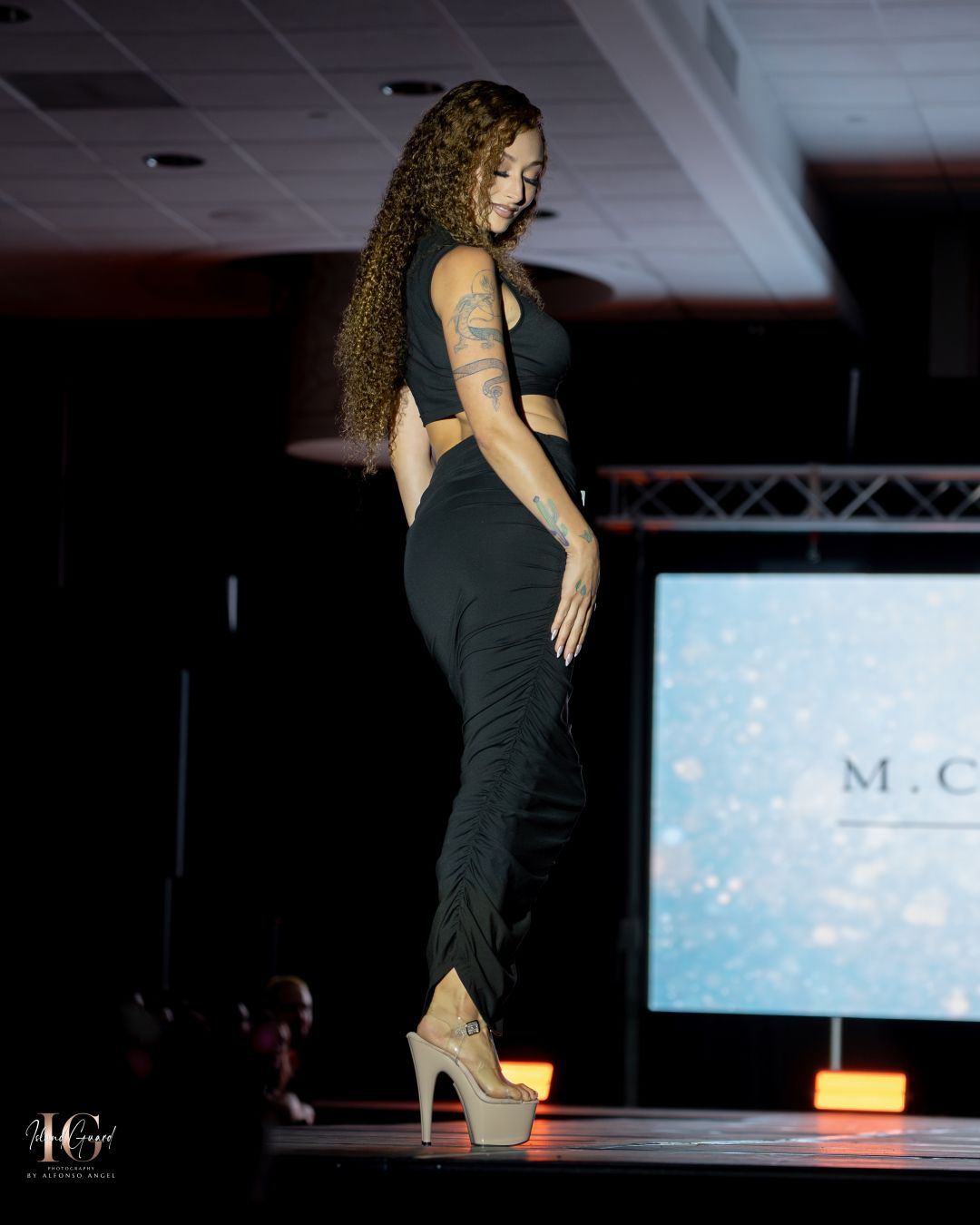Model showcases fitted black two-piece outfit with platform heels.
