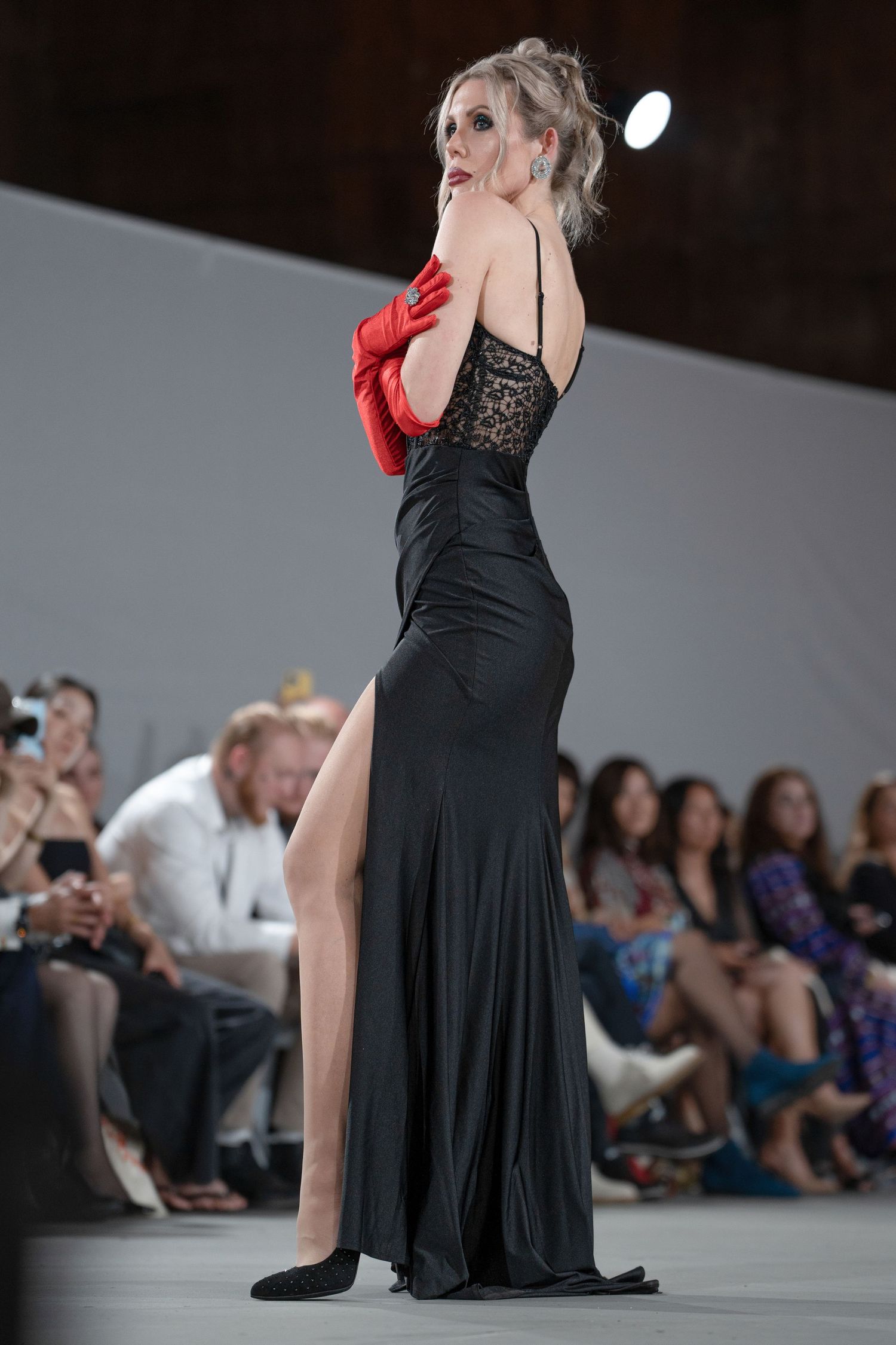 Dancers perform an elegant sequence in black dresses during a contemporary dance show with an audience watching.