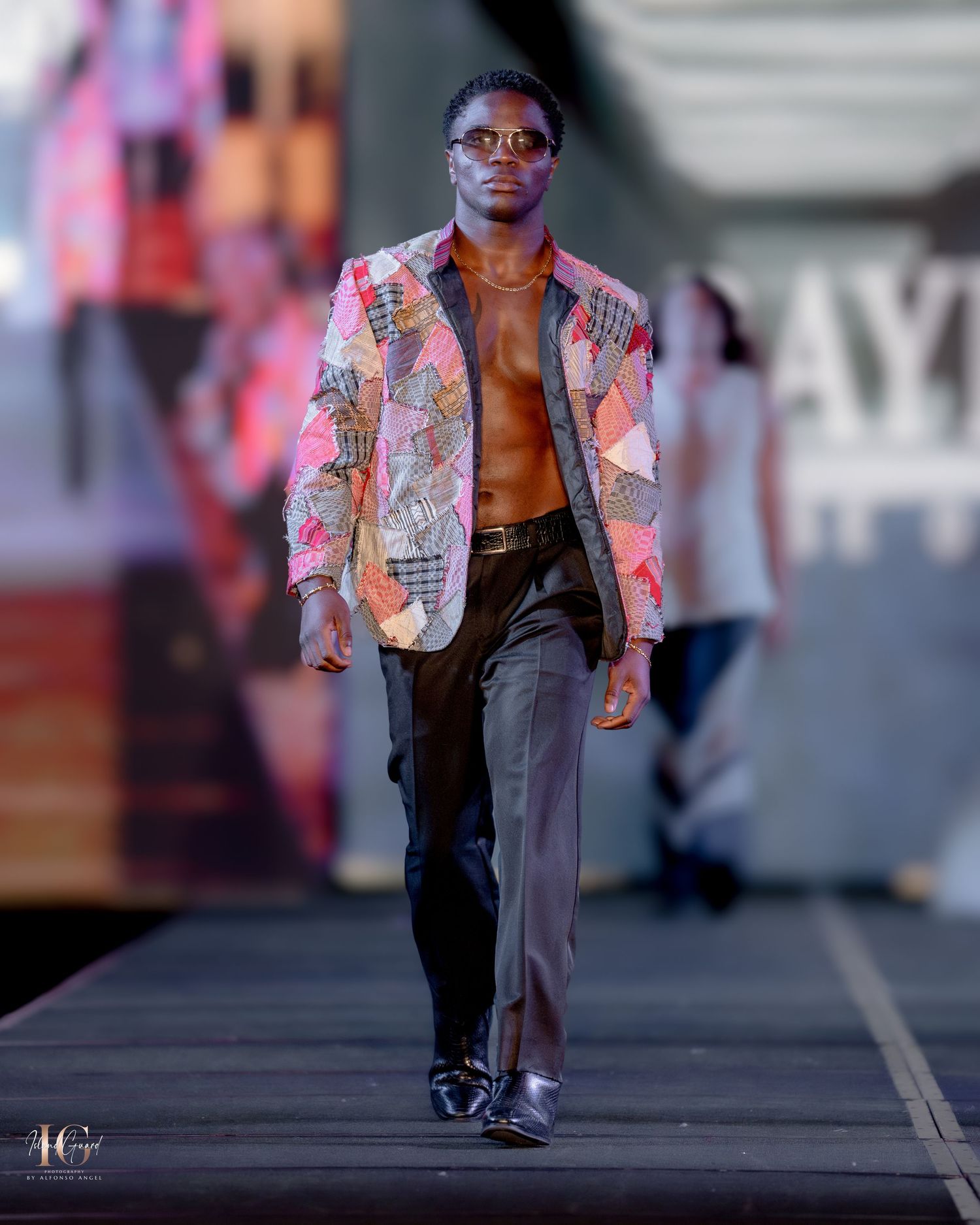 Model wearing pink and orange patterned blazer with dark pants on catwalk.