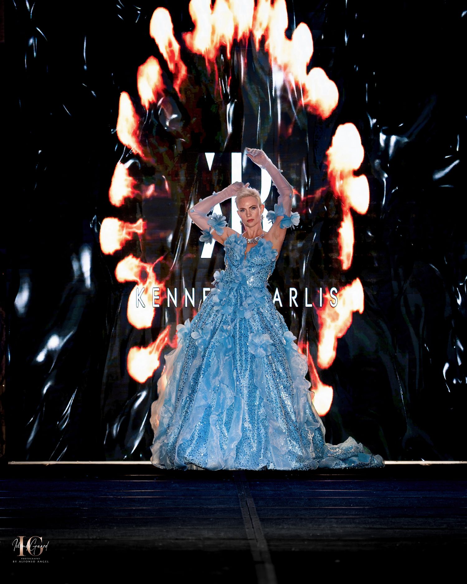Dramatic ballgown presentation with light ring effect and blue sparkly dress on dark stage.
