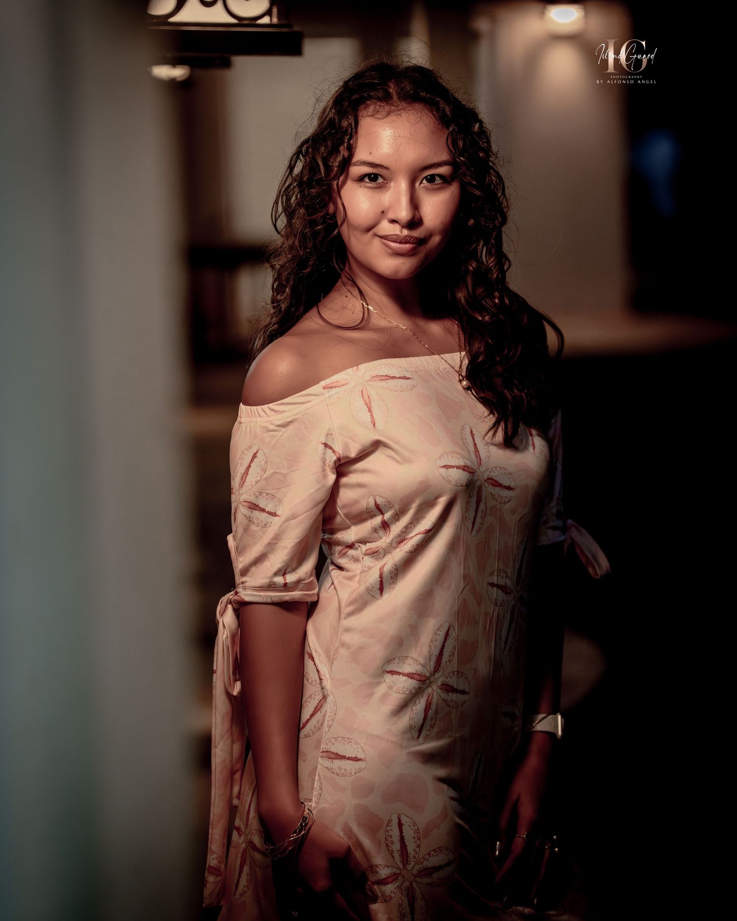 Portrait of a young person in a beige top against a dark background with moody lighting.