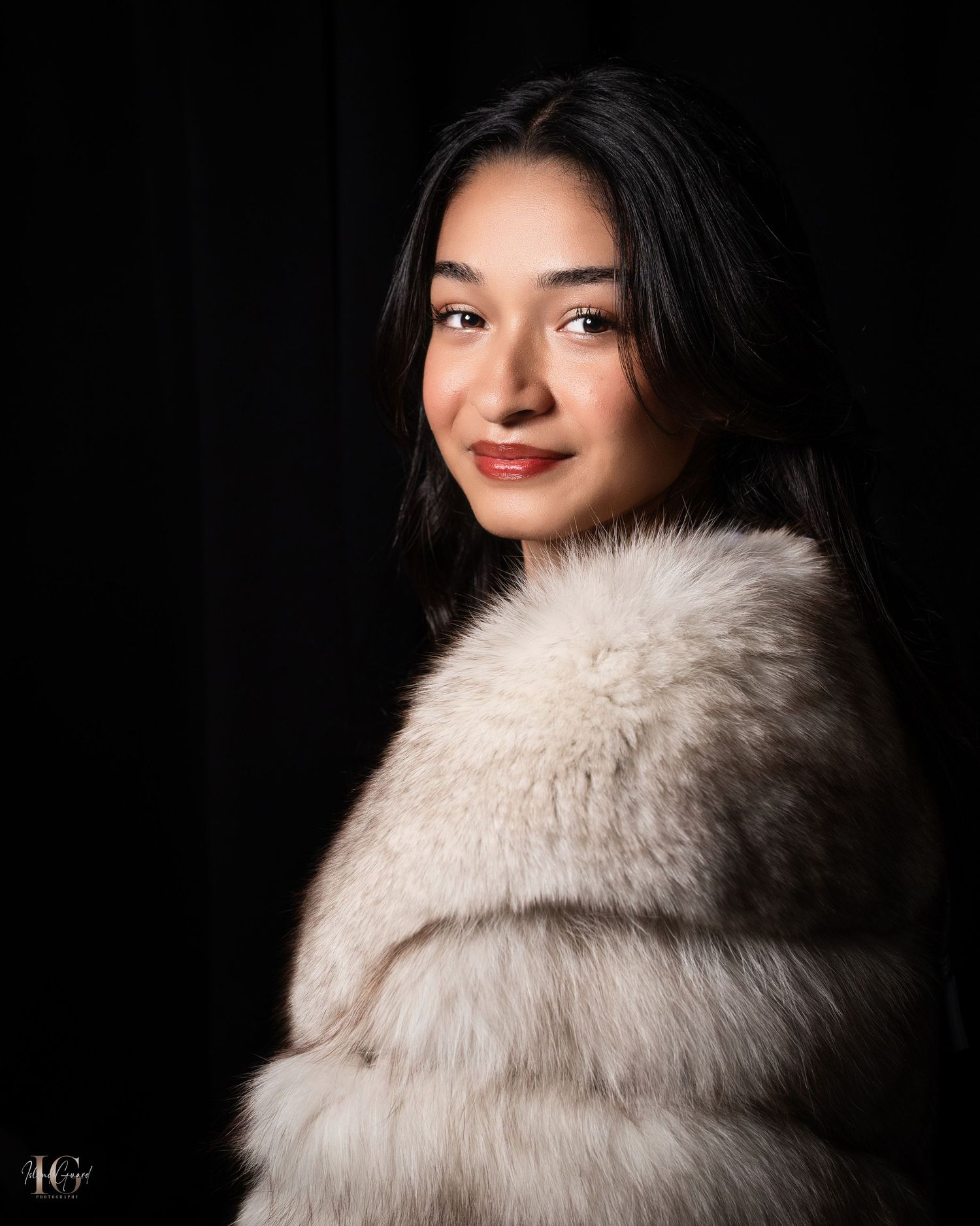 Elegant portrait in cream fur coat against dark background with soft side lighting.