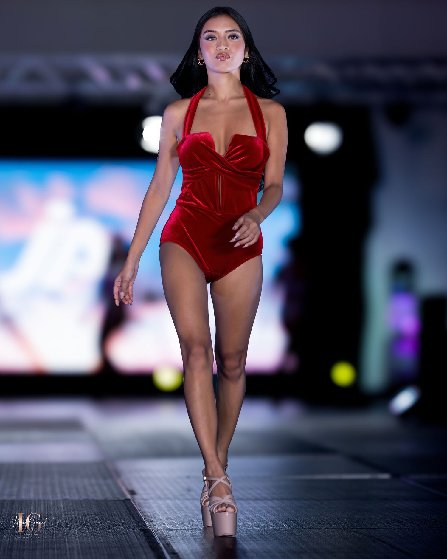 Luxurious red velvet swimsuit collection presented on dark runway with dramatic spotlighting.