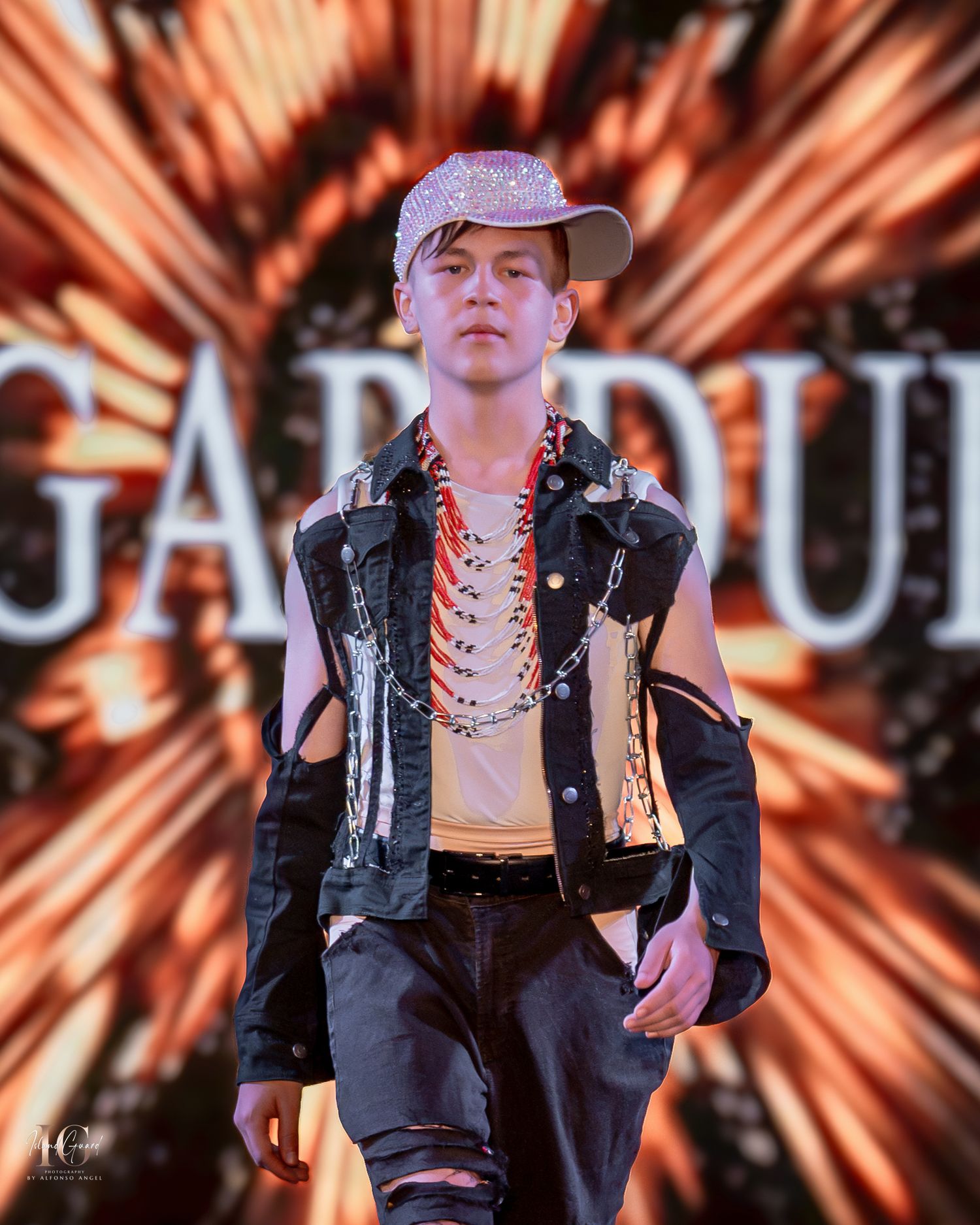 Edgy fashion runway look featuring leather vest, baseball cap and orange background effects.