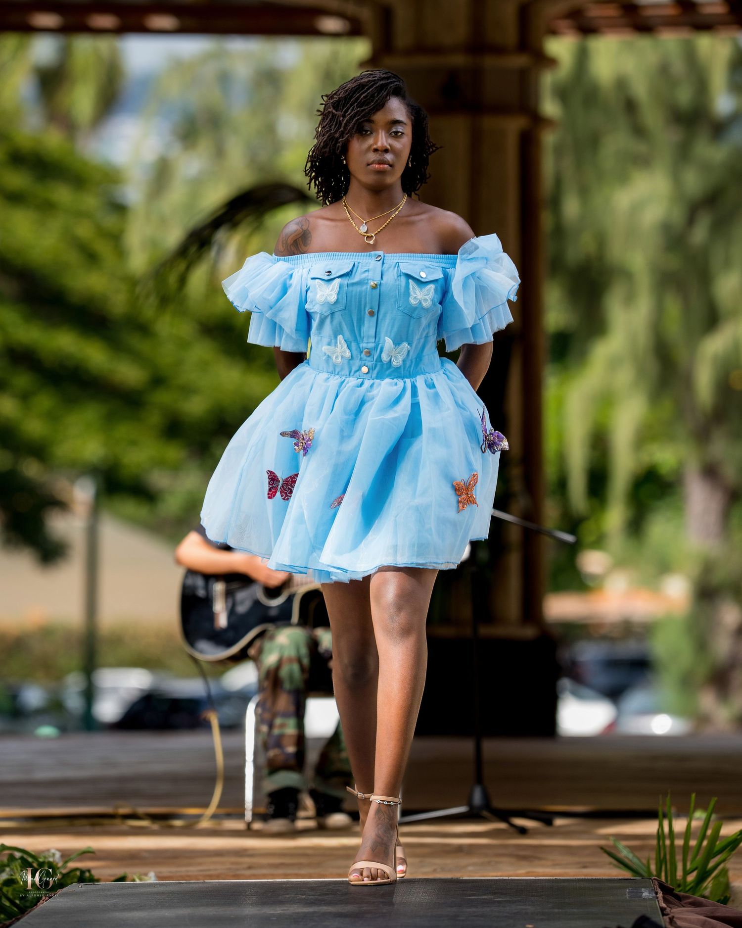 Light blue off-shoulder dress with butterfly details shown from different angles on a wooden deck outdoors.