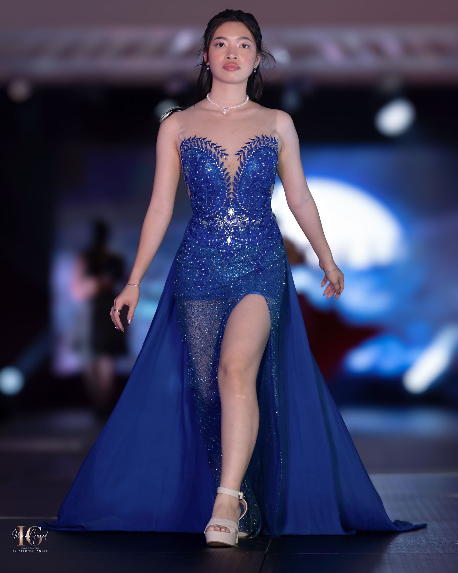 Sparkling royal blue evening gown with sweetheart neckline and thigh-high slit on fashion catwalk.