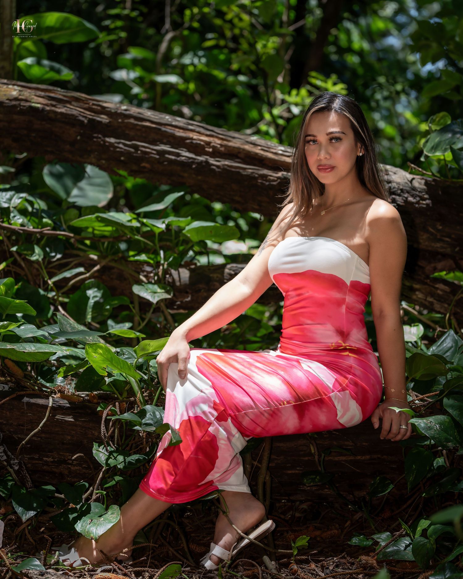 A person in a coral-colored dress reclining on a fallen log in a lush forest setting, creating a dreamy woodland scene.