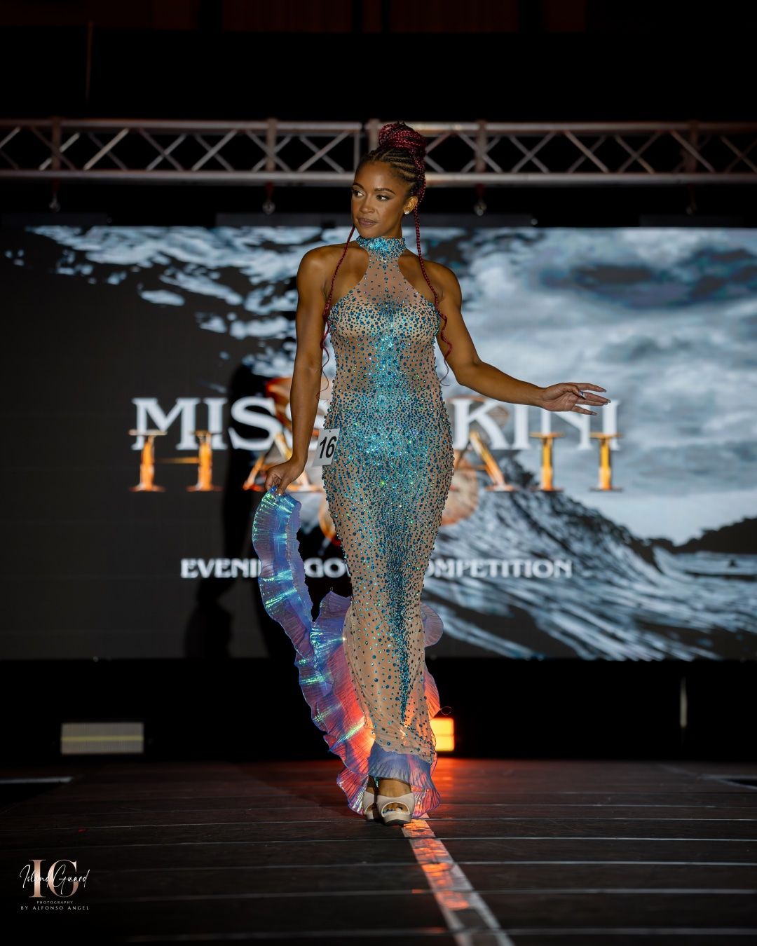 A model walks the runway in a sparkling turquoise evening gown during a Miss Kenya fashion competition event.