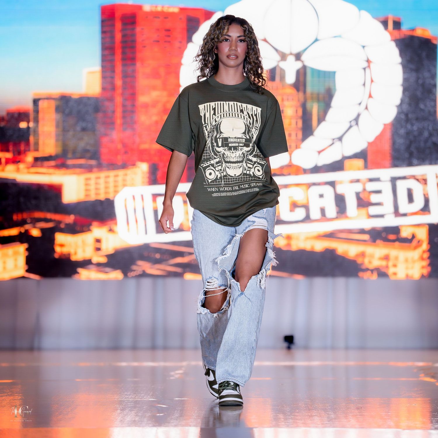 Models walking runway in casual streetwear with urban sunset backdrop.