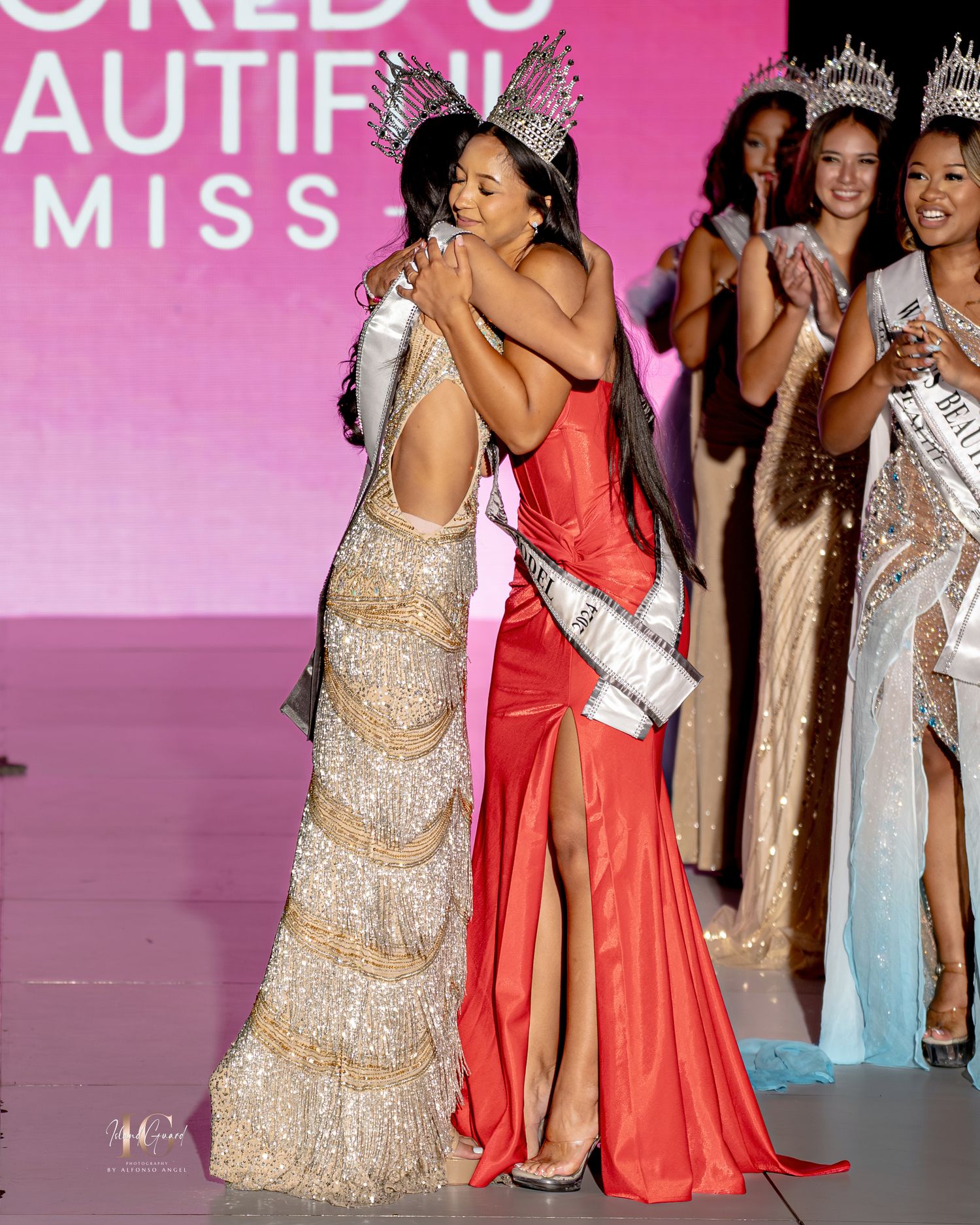 Contestants in evening gowns gather on stage at a beauty pageant with pink backdrop and lighting.