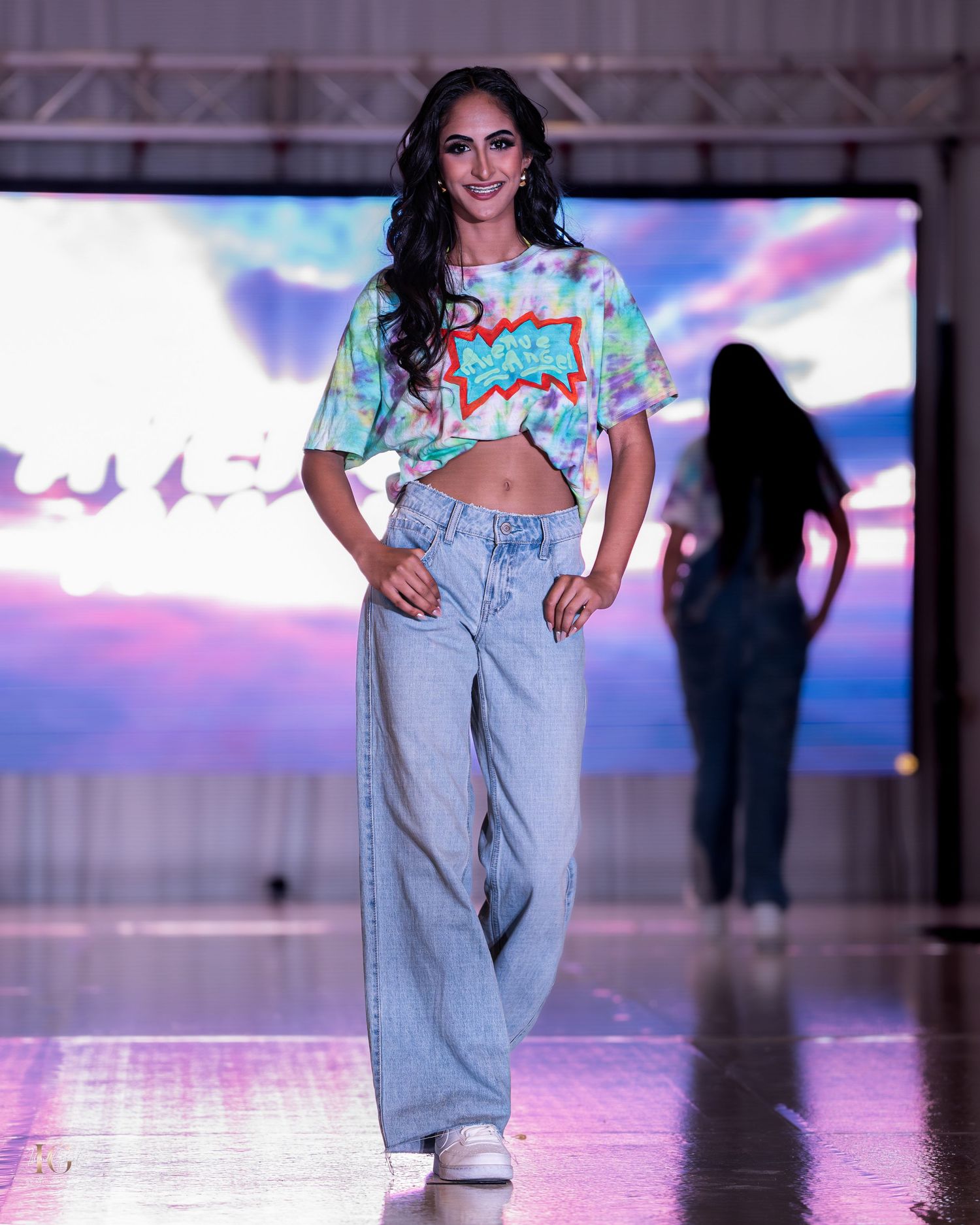 Models walk the runway wearing casual denim looks with cropped tops during a fashion show presentation.