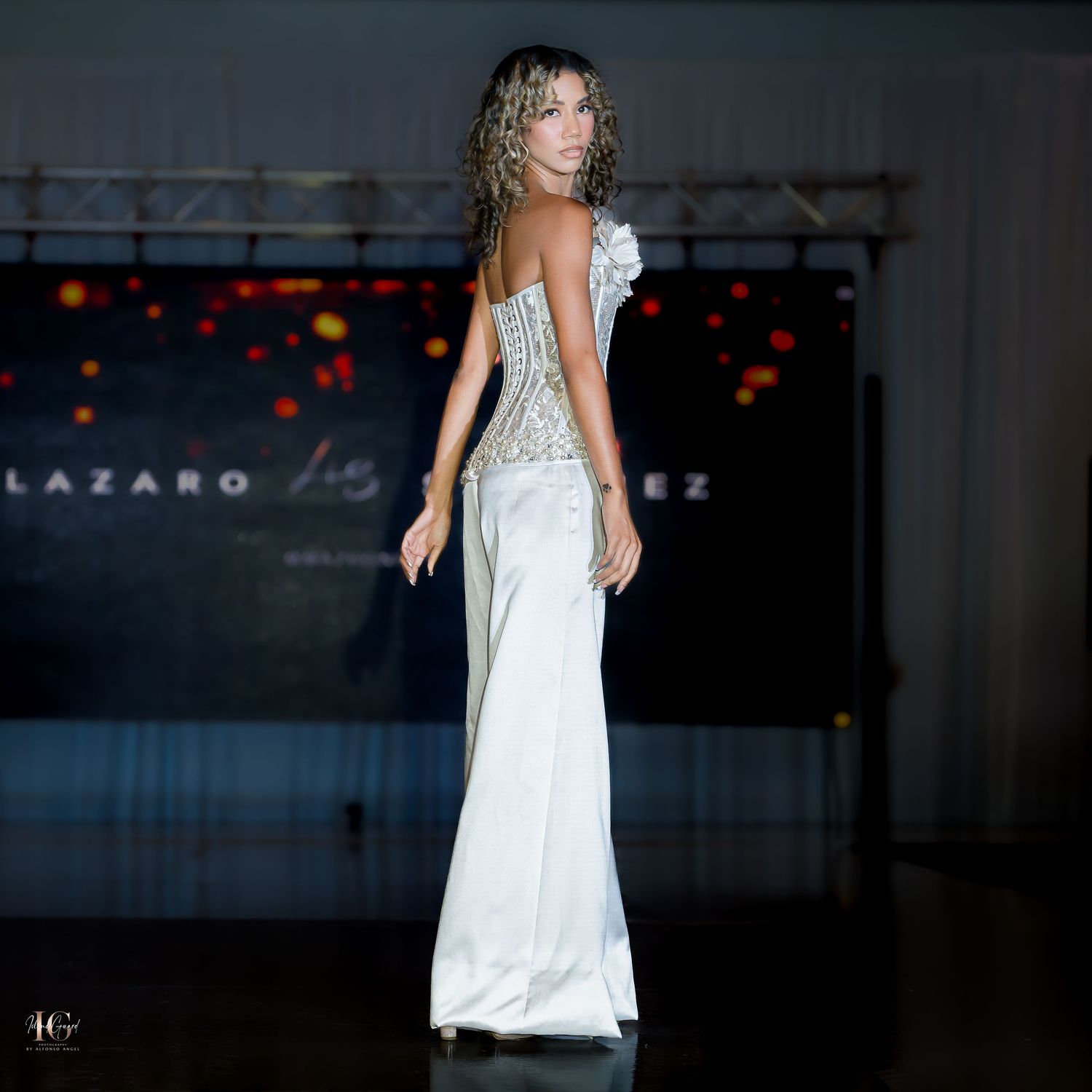 Elegant white evening wear with fitted bodice and flowing pants shown on runway.