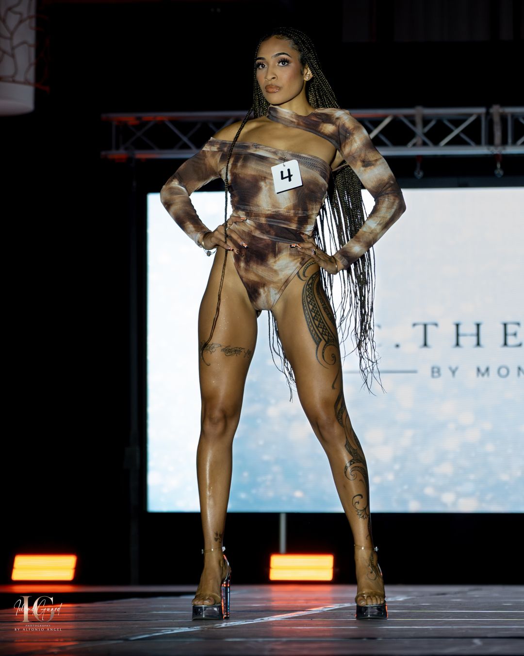 Model showcases abstract body art design in metallic tones on fashion runway.