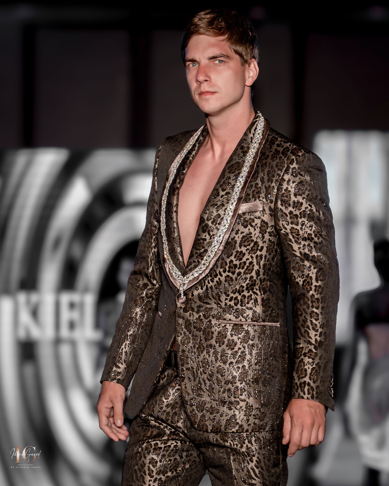 Metallic brocade blazer in gold and brown tones presented on fashion runway.