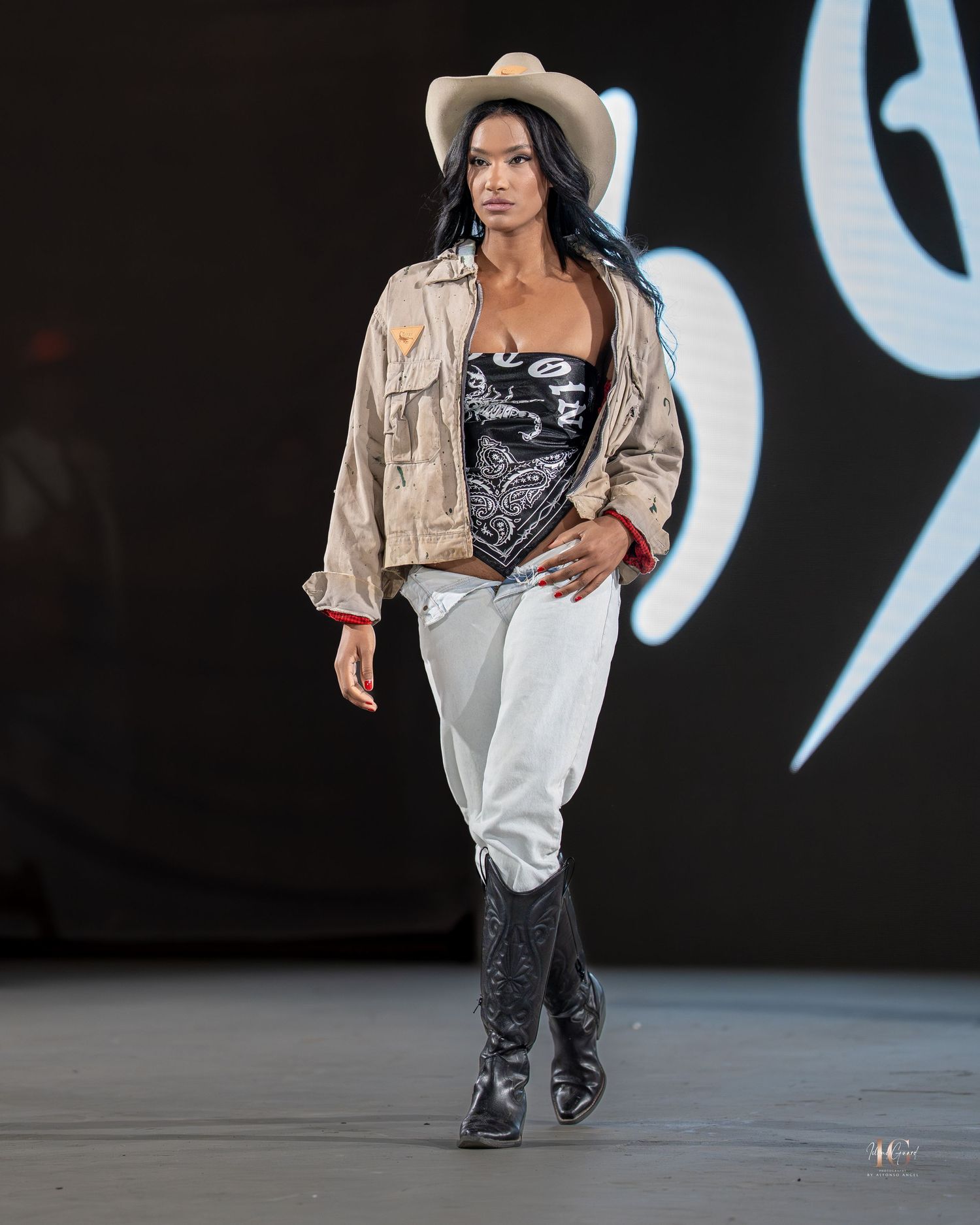 Models walk the runway showcasing urban streetwear designs against a dark backdrop at a fashion show.
