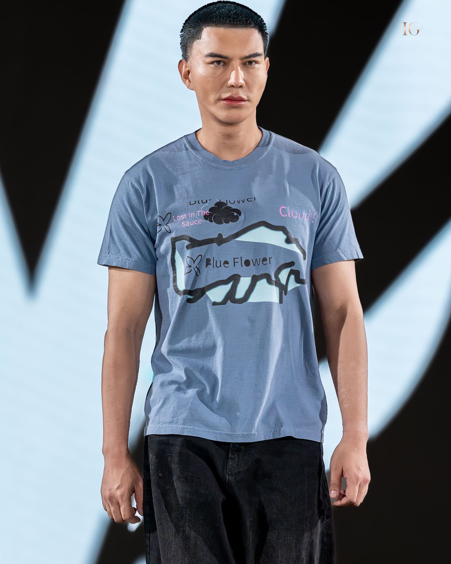 A person wearing a gray graphic t-shirt with a buffalo design stands against a black and white striped background.