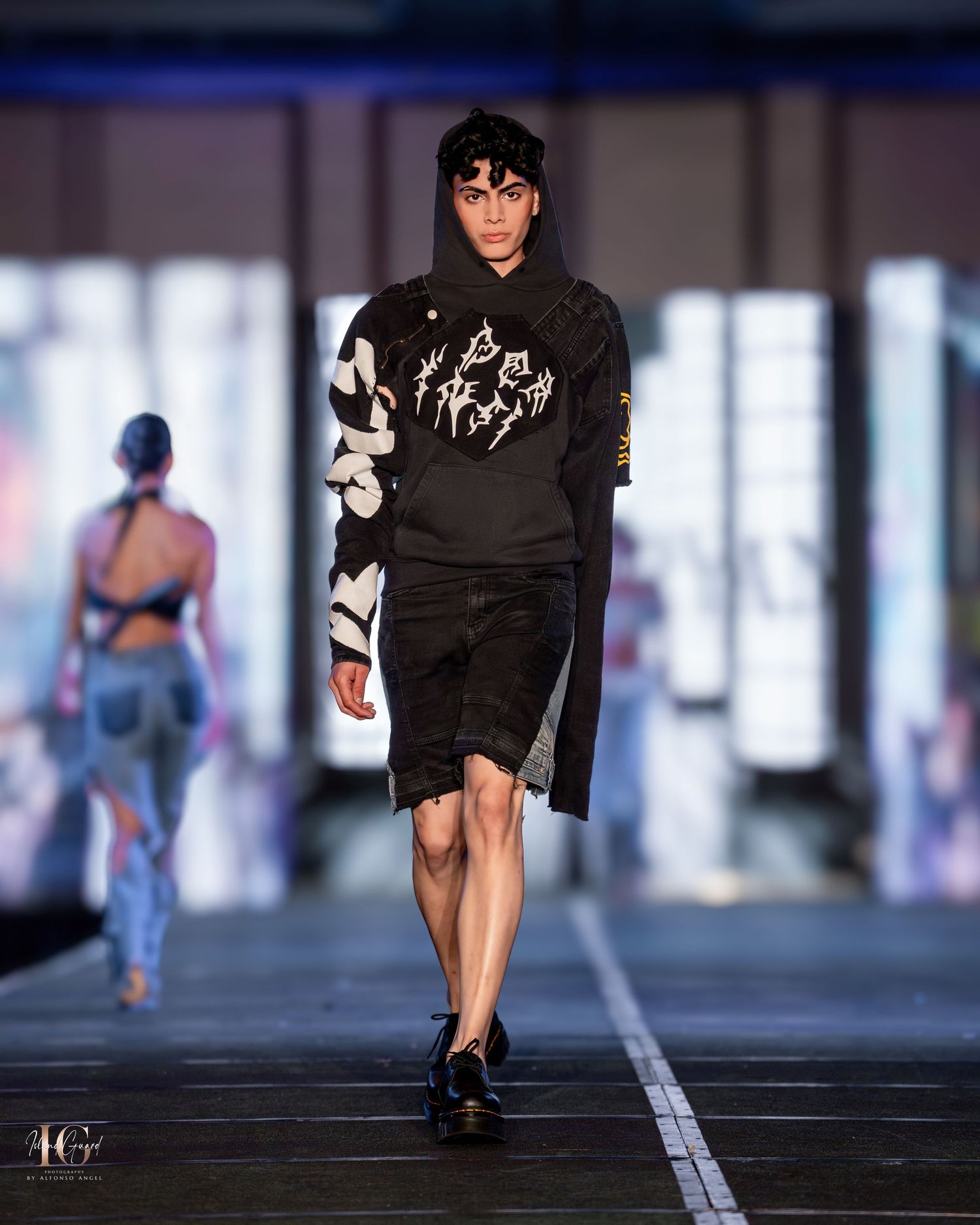 Model walks runway in black and white printed sweater and knee-length skirt.