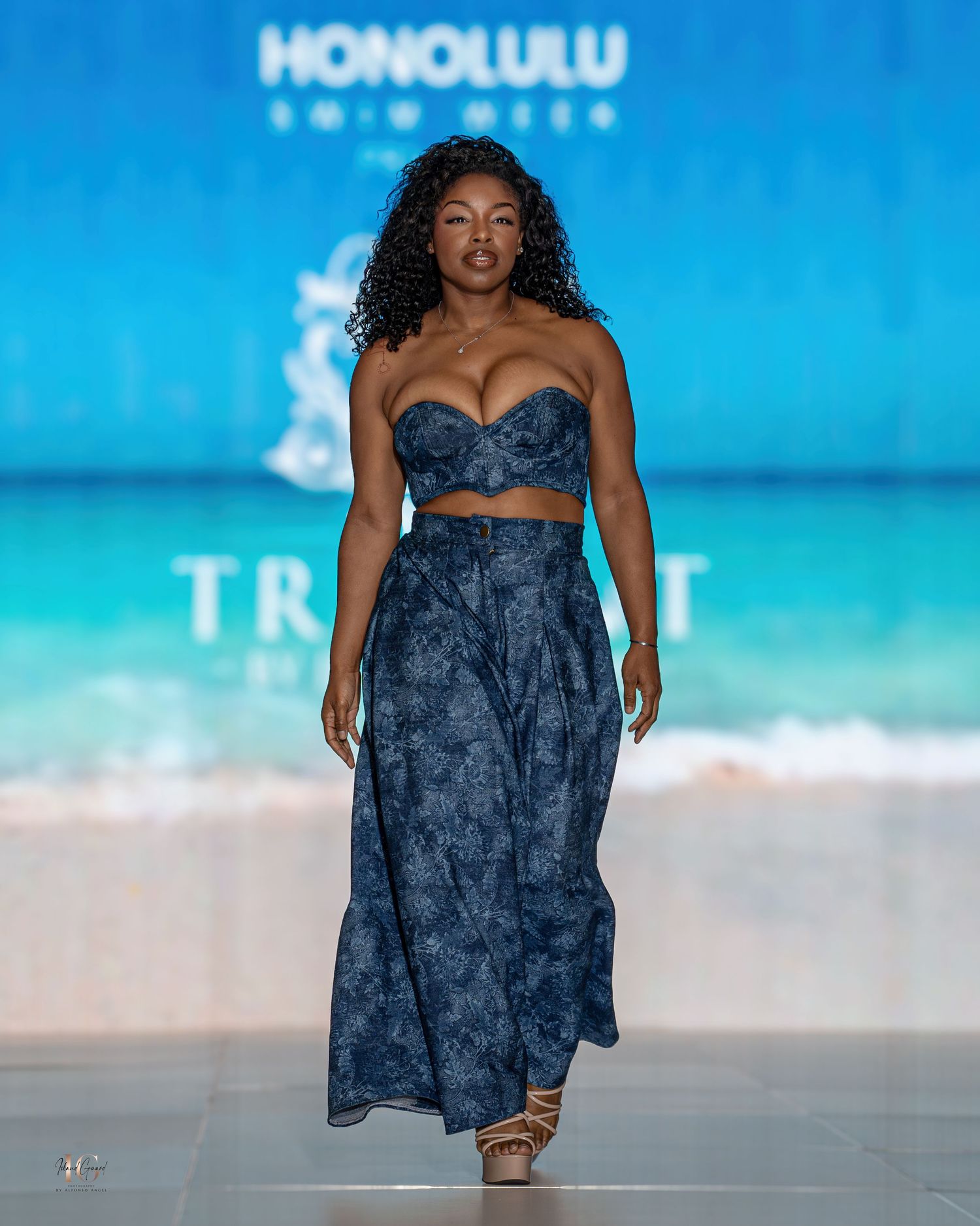 Navy blue resort dress with sweetheart neckline presented on beachy runway at Honolulu fashion show.