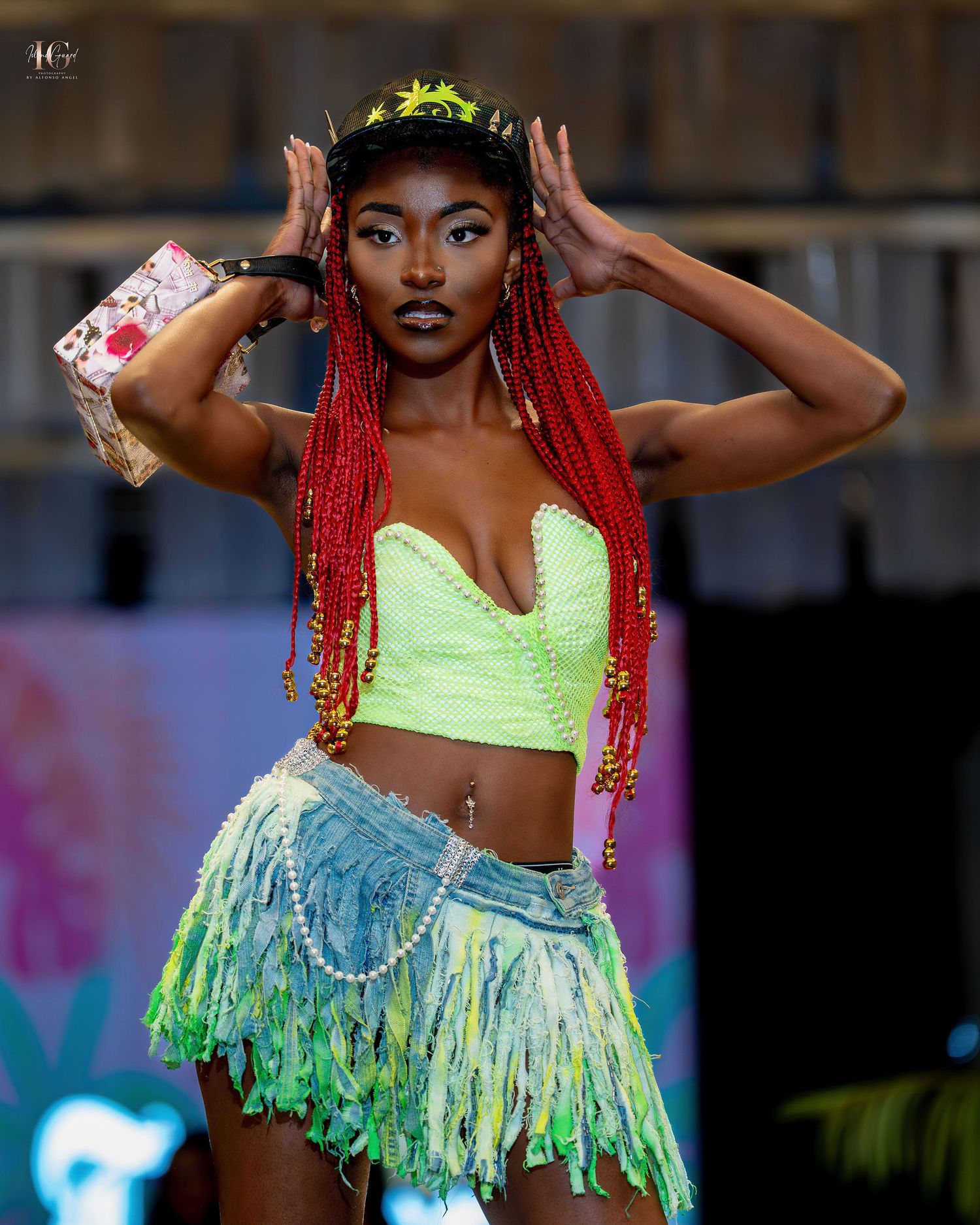Dancer in neon yellow crop top and fringed skirt performs dynamic dance moves on stage with colorful lighting.
