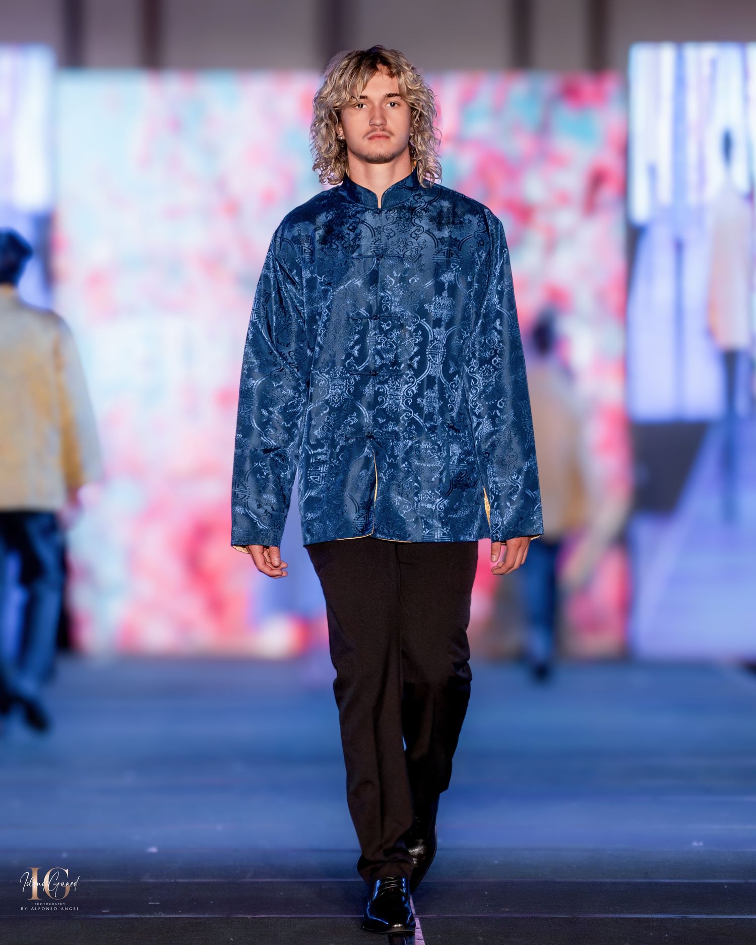 Navy blue textured jacket paired with black trousers shown on fashion runway.