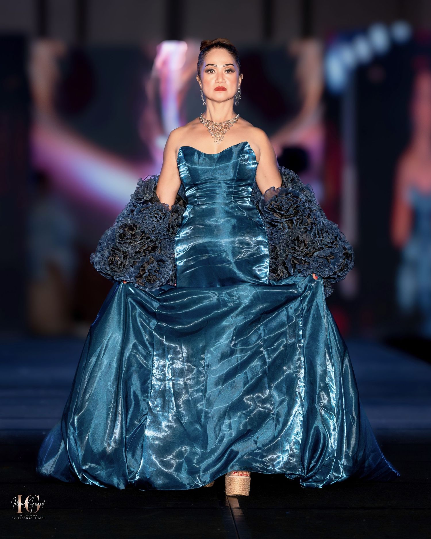 Teal satin ball gown with dramatic black ruffle sleeves on fashion runway.