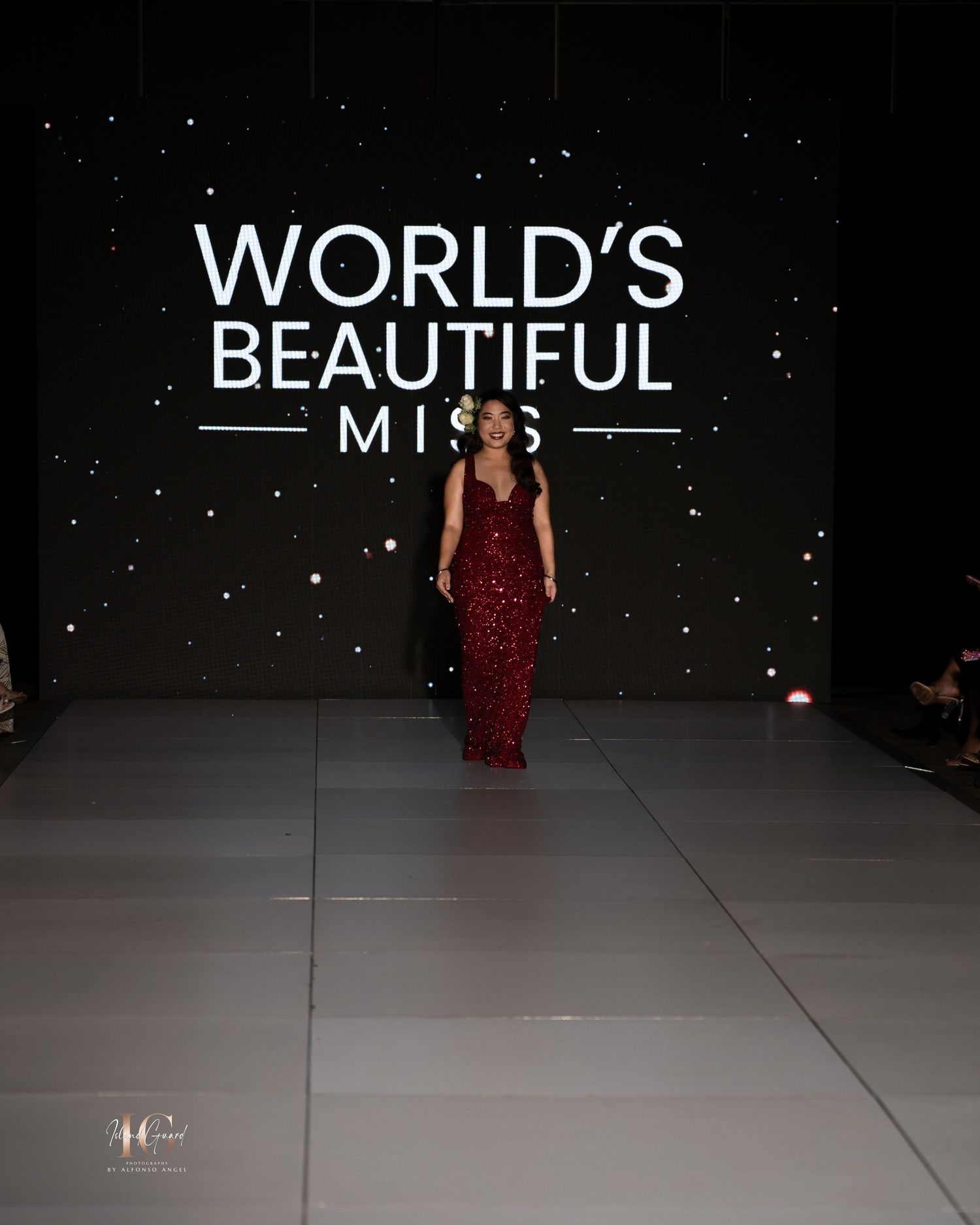 A model walks the runway in a sparkling red evening gown at the World's Beautiful fashion show.