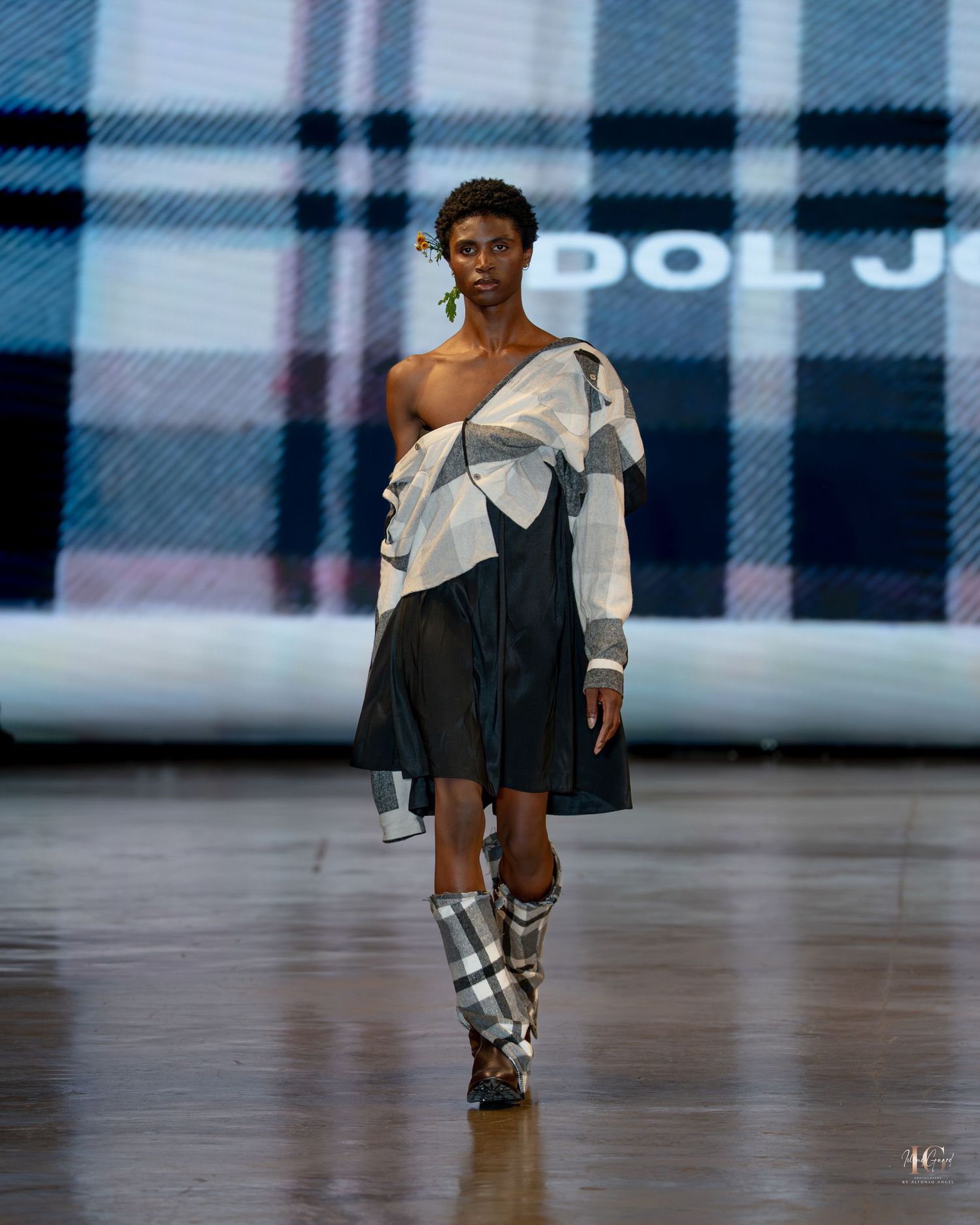 Models walk the runway wearing black and white designer outfits and knee-high boots during a fashion show.