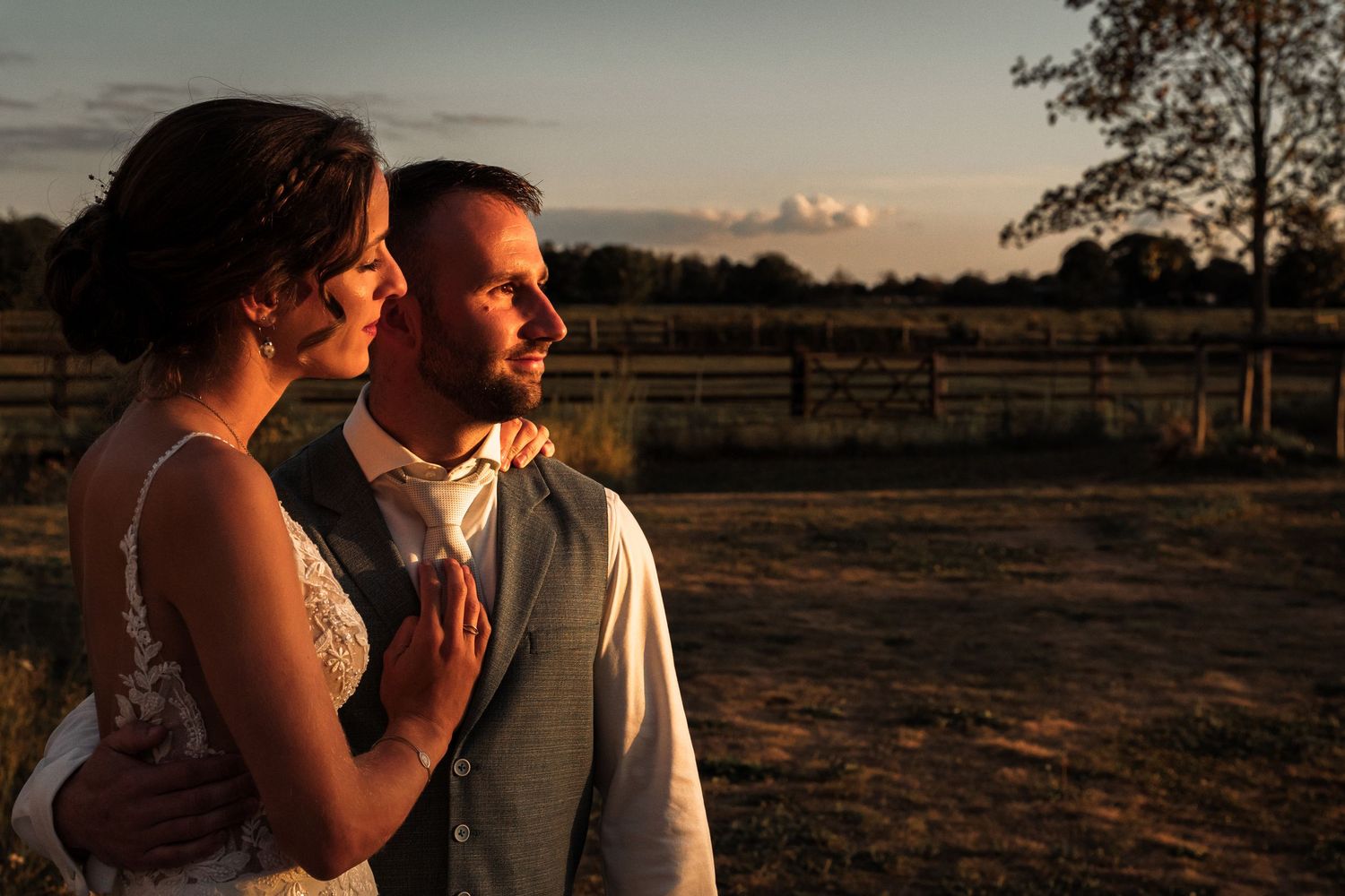 A couple shares an intimate moment together during sunset in a rustic outdoor setting.
