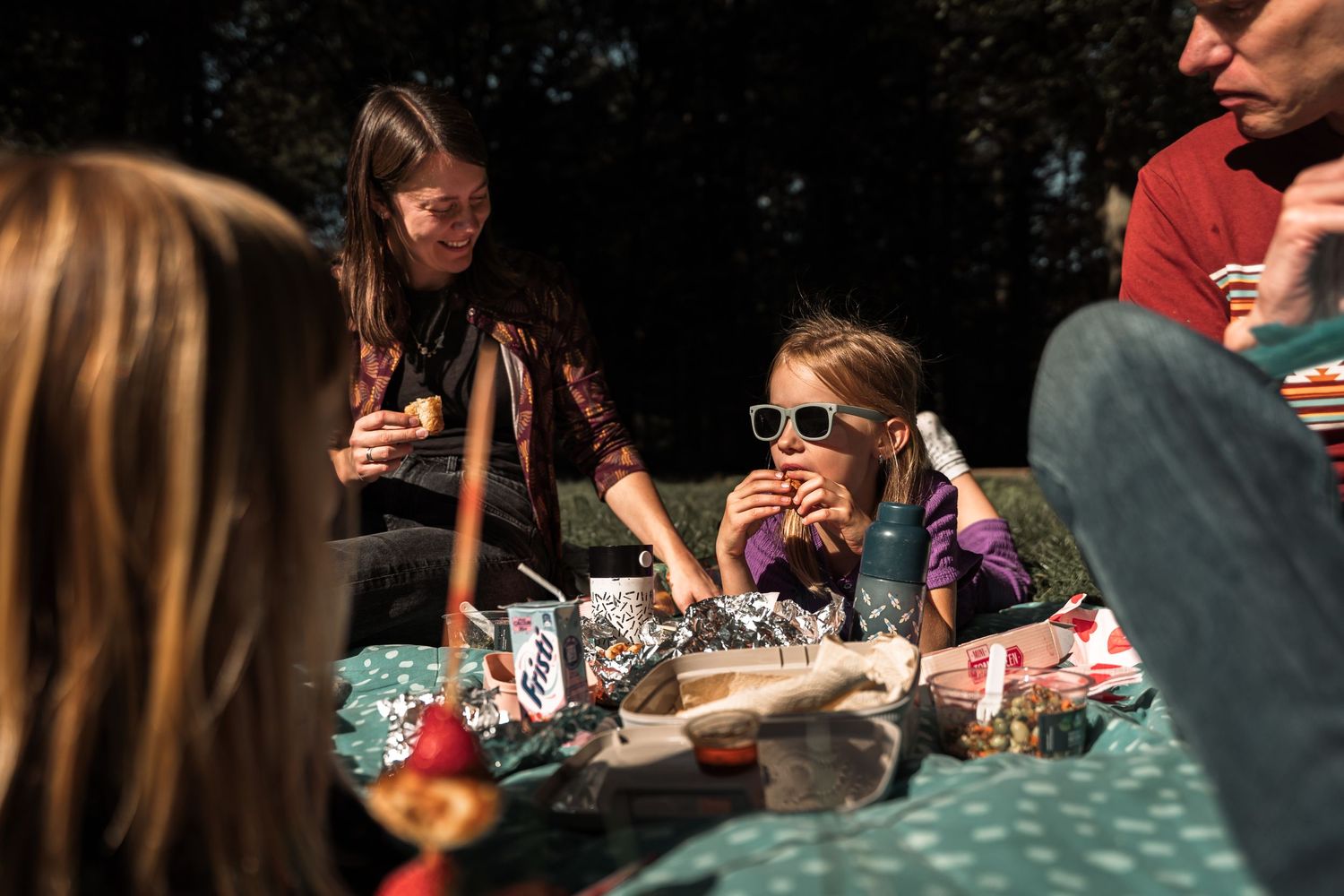 People enjoying outdoor dining and conversation at a picnic table.