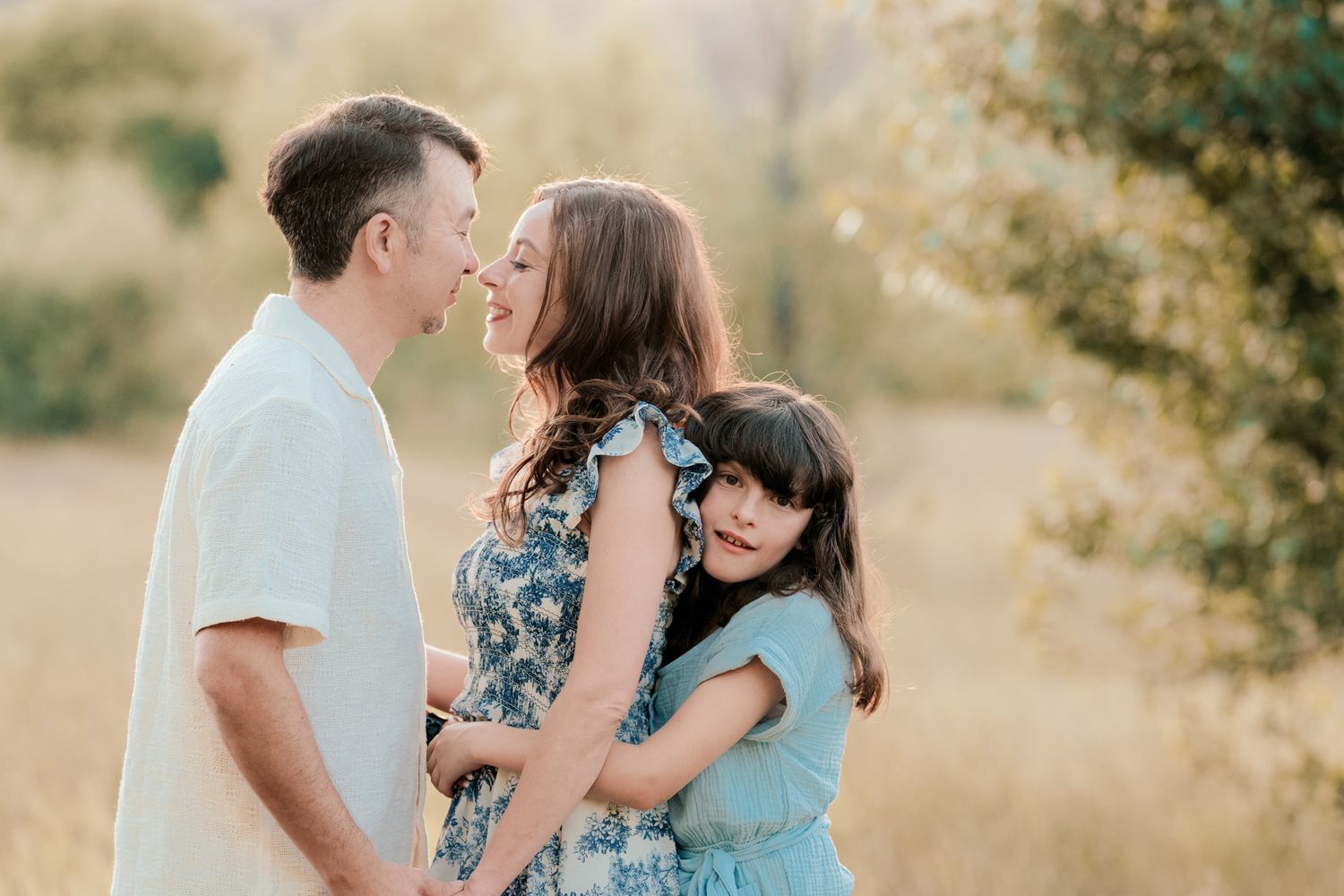 Family sharing an intimate moment together outdoors at sunset.