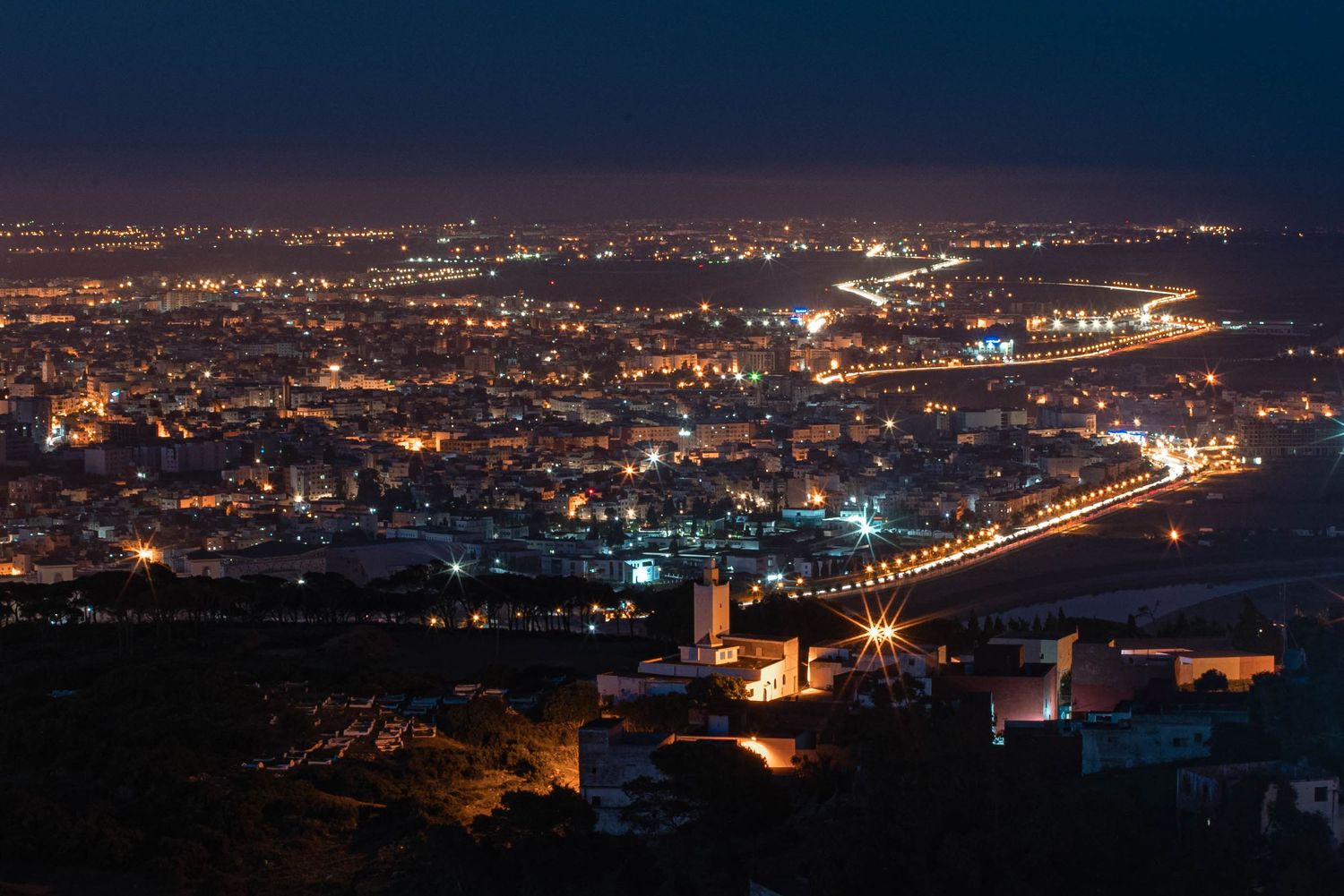 Panoramic view of a city skyline at night with twinkling lights stretching across the horizon.