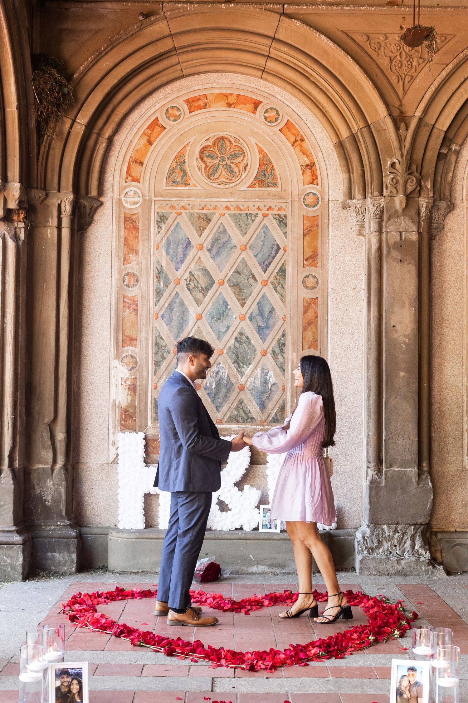 proposal under bethesda terrace with petals in a red heart, candles and initials sign and photos