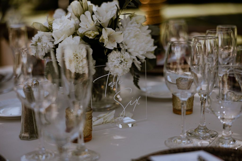 Elegant white floral centerpieces adorn tables set with crystal glassware at a formal dining event.