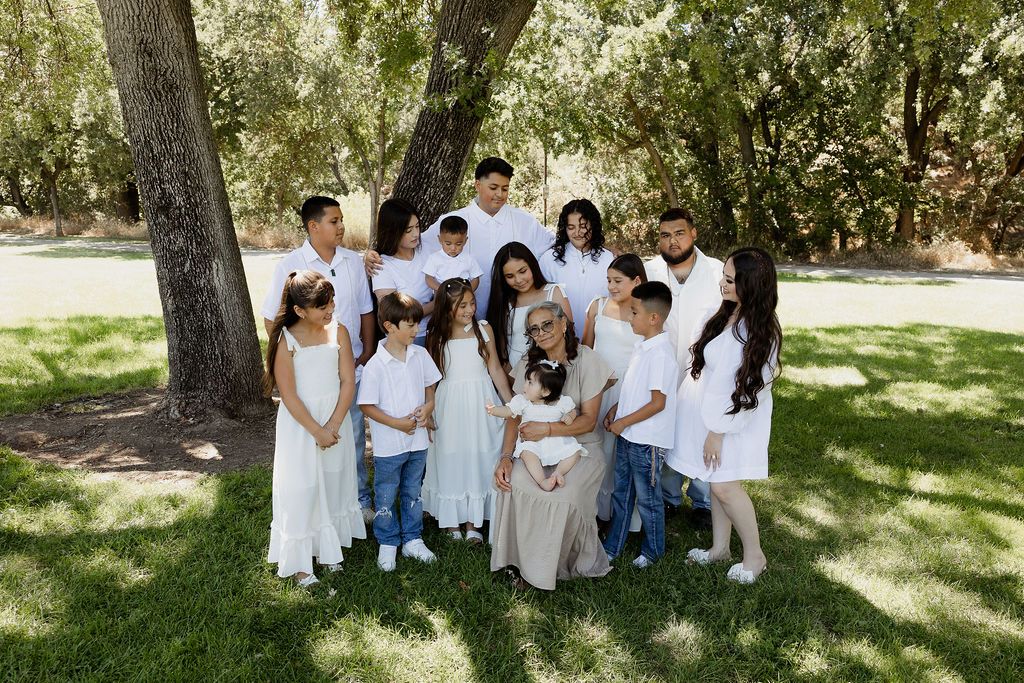 A group wearing coordinated white and blue outfits poses together in a sunny outdoor garden setting.