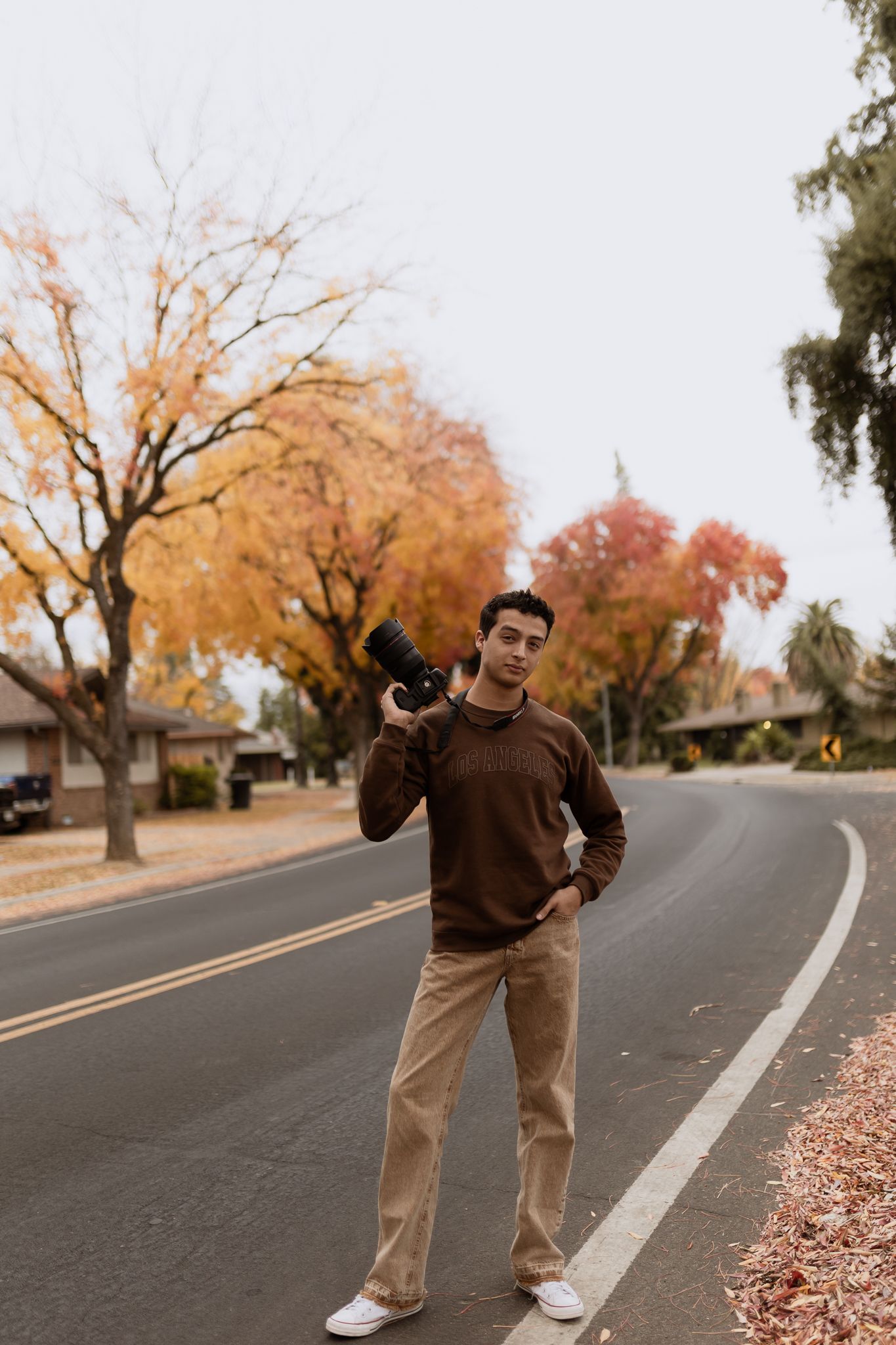 Series of photos showing person in brown sweater and khaki pants posing in casual stances on an autumn street with falling leaves.