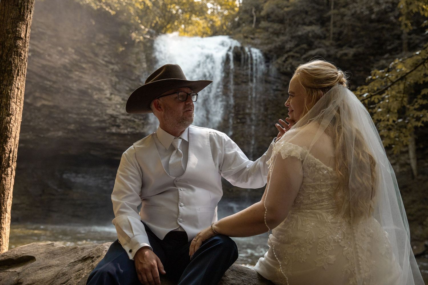 newly weds have their wedding photographer capture a wedding portrait in front of a waterfall at cloudland state park in georgia