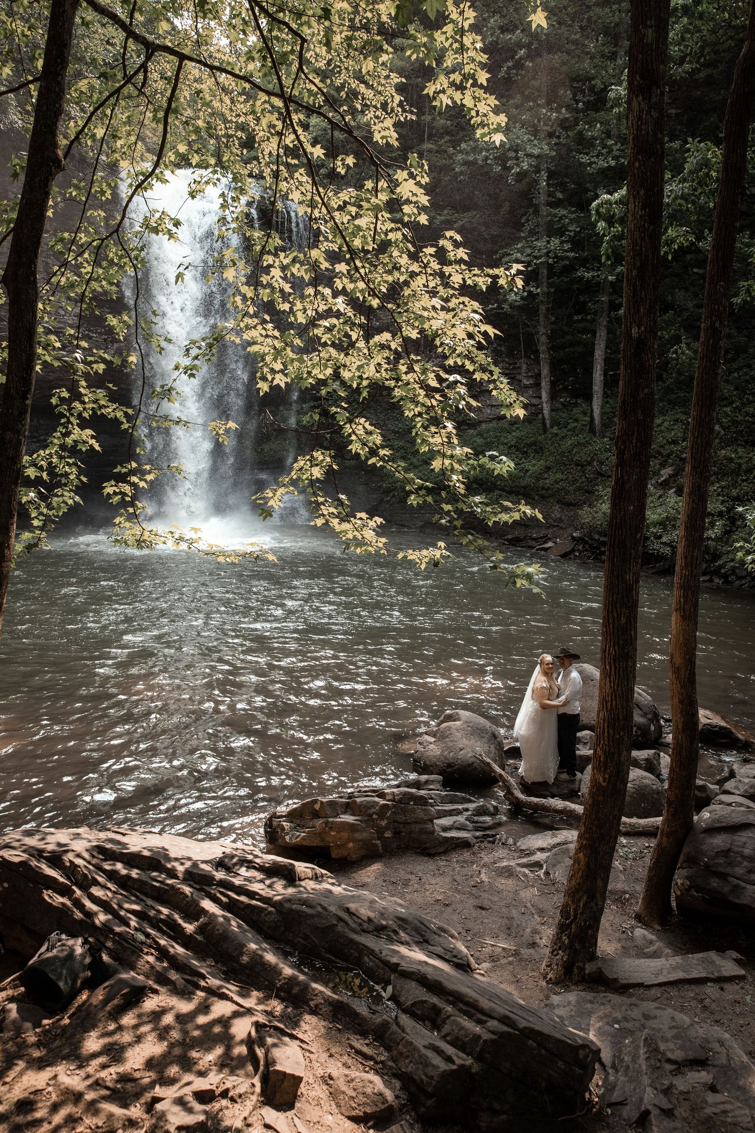 newly weds have their wedding photographer capture a wedding portrait in front of a waterfall at cloudland state park in georgia