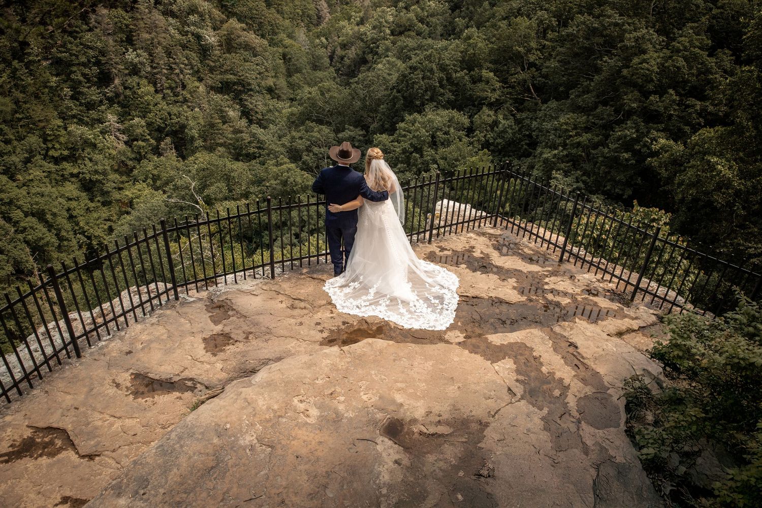 newly weds have their wedding photographer capture a wedding portrait in front of a cliff at cloudland state park in georgia