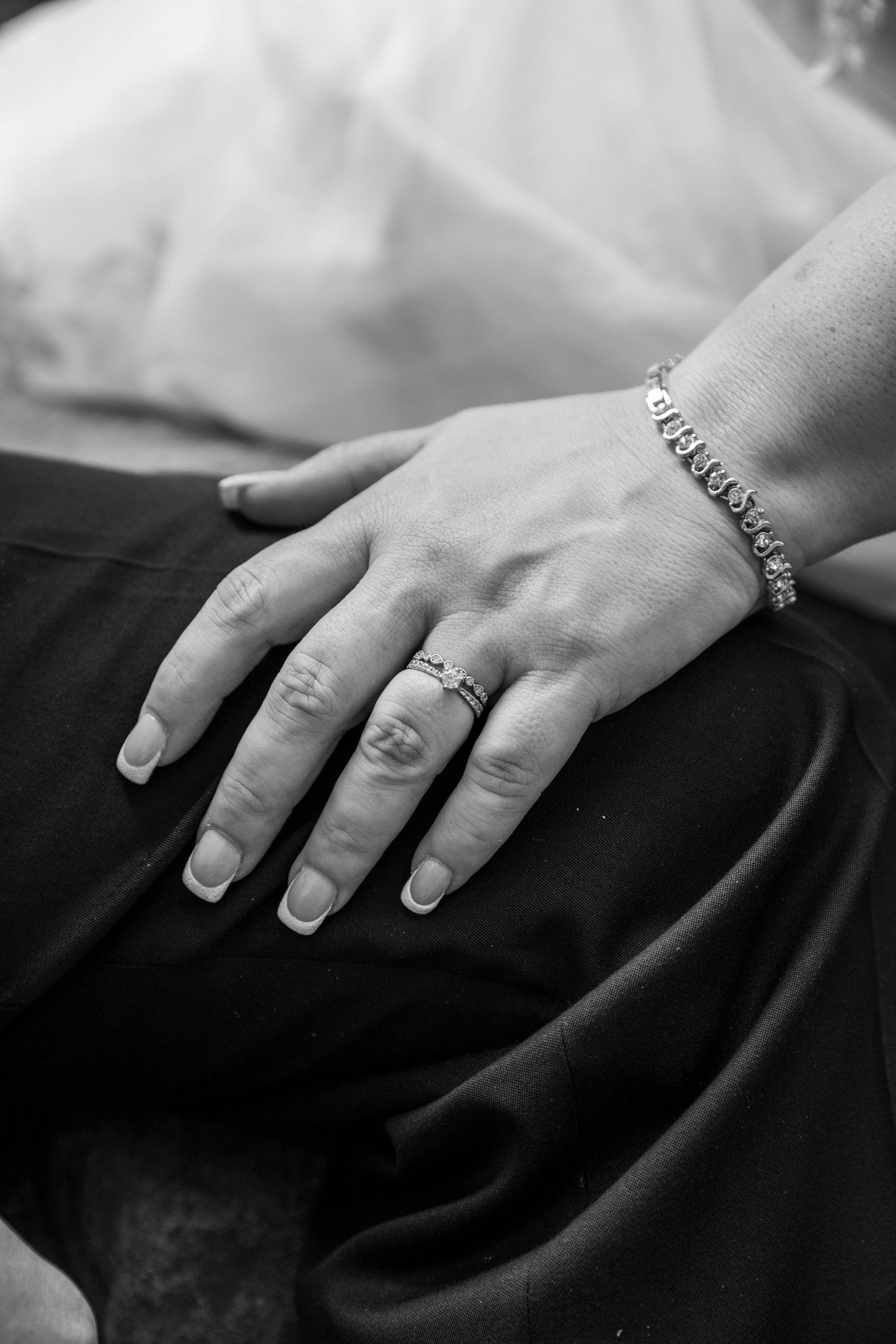 A detail photograph of a brides wedding ring on her newly wed husband's thigh