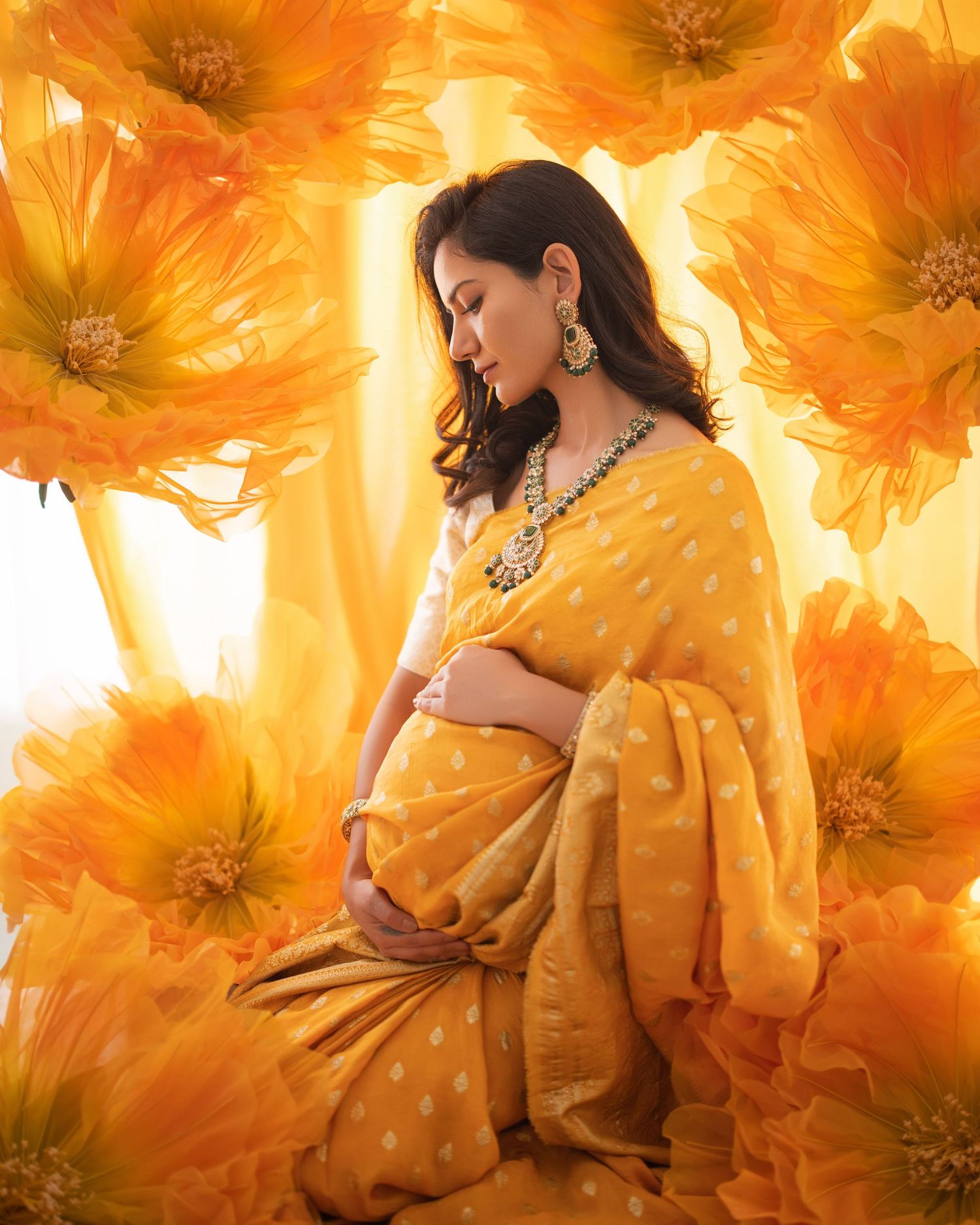 A maternity portrait against golden marigolds features a yellow sari-clad figure in gentle contemplation.