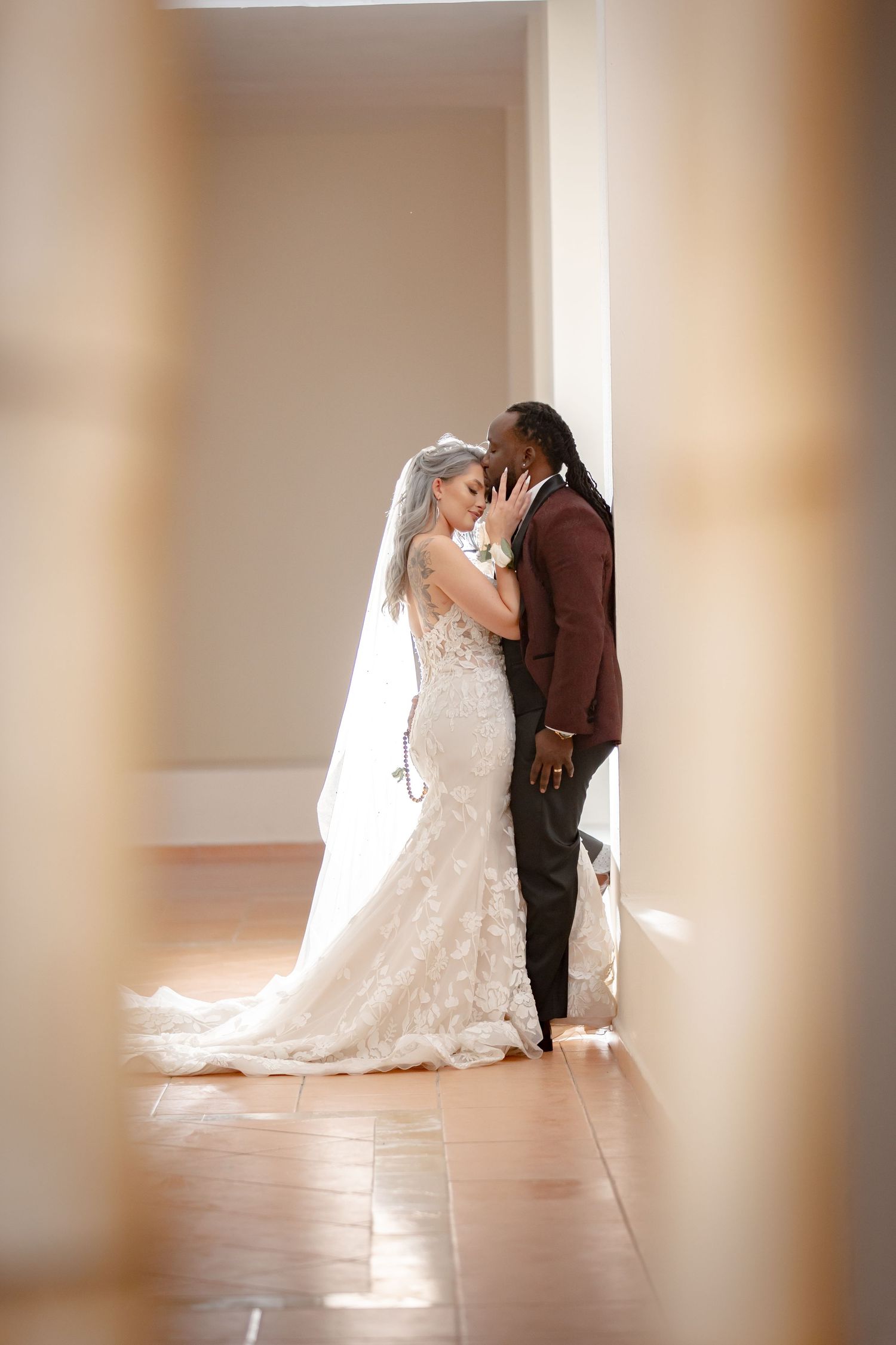 Intimate wedding portrait through doorframe with natural lighting.