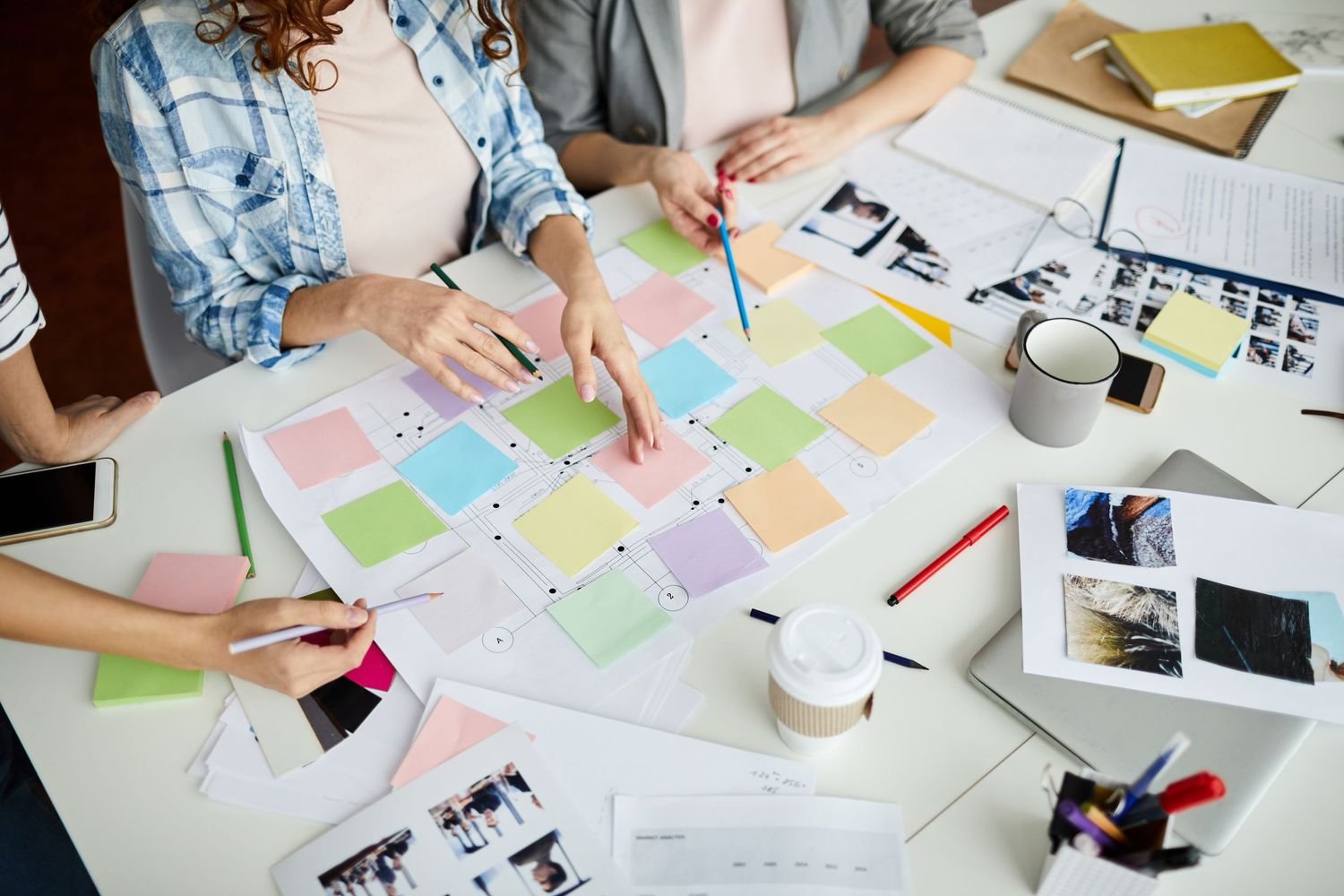 Overhead view of creative team brainstorming with colorful sticky notes and materials on table.